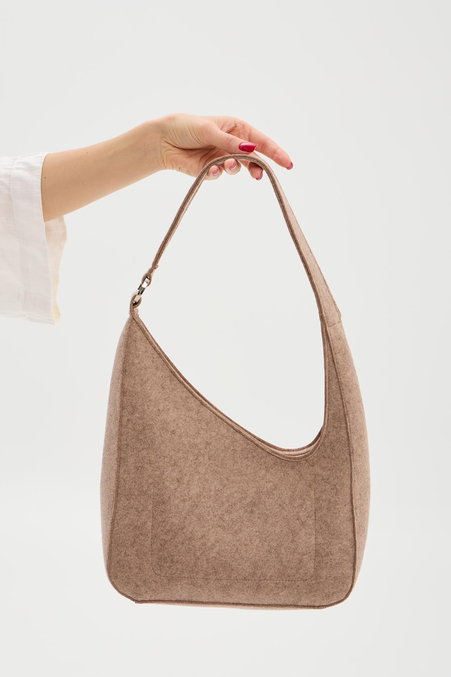Beige handbag held by a person against a white background