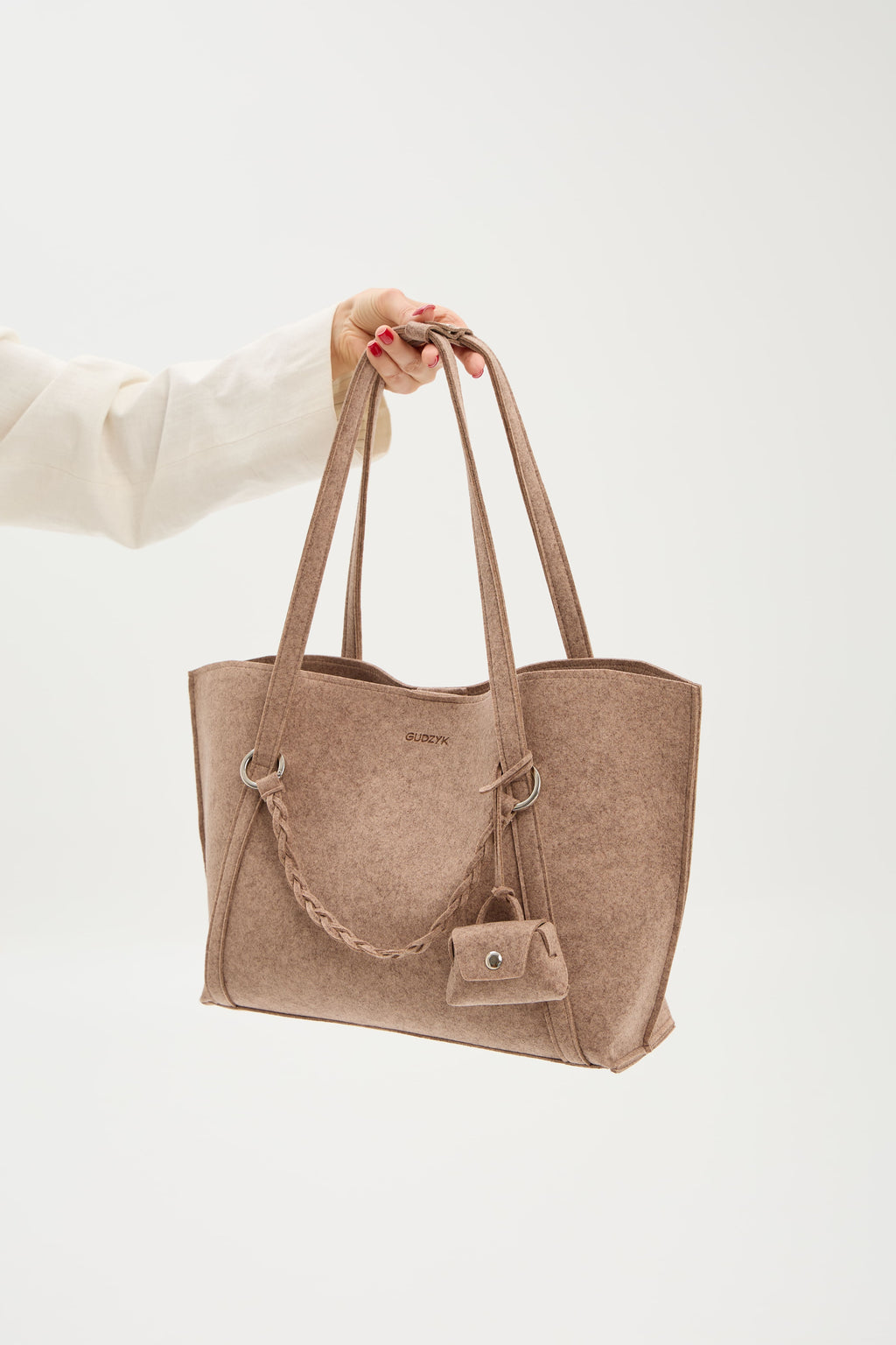Beige tote bag held by a person on a white background