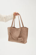 Beige tote bag held by a person on a white background