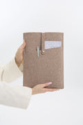 Beige felt case with a pocket held by a person on a white background