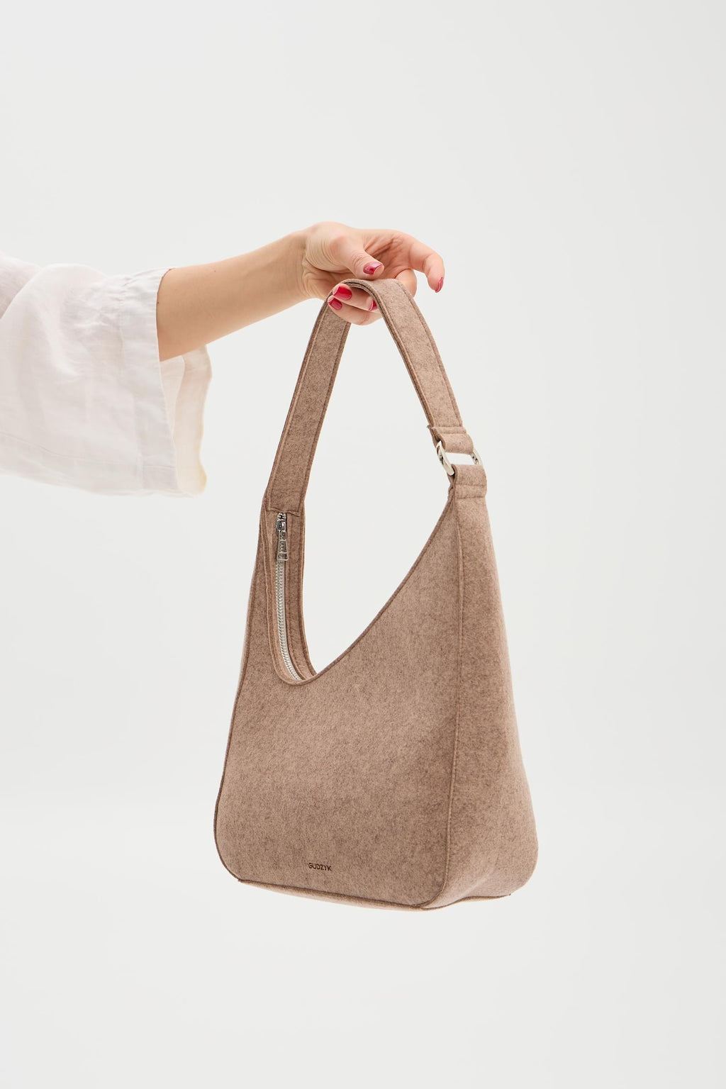 Beige handbag held by a person against a white background
