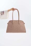 Beige handbag held by a hand against a white background