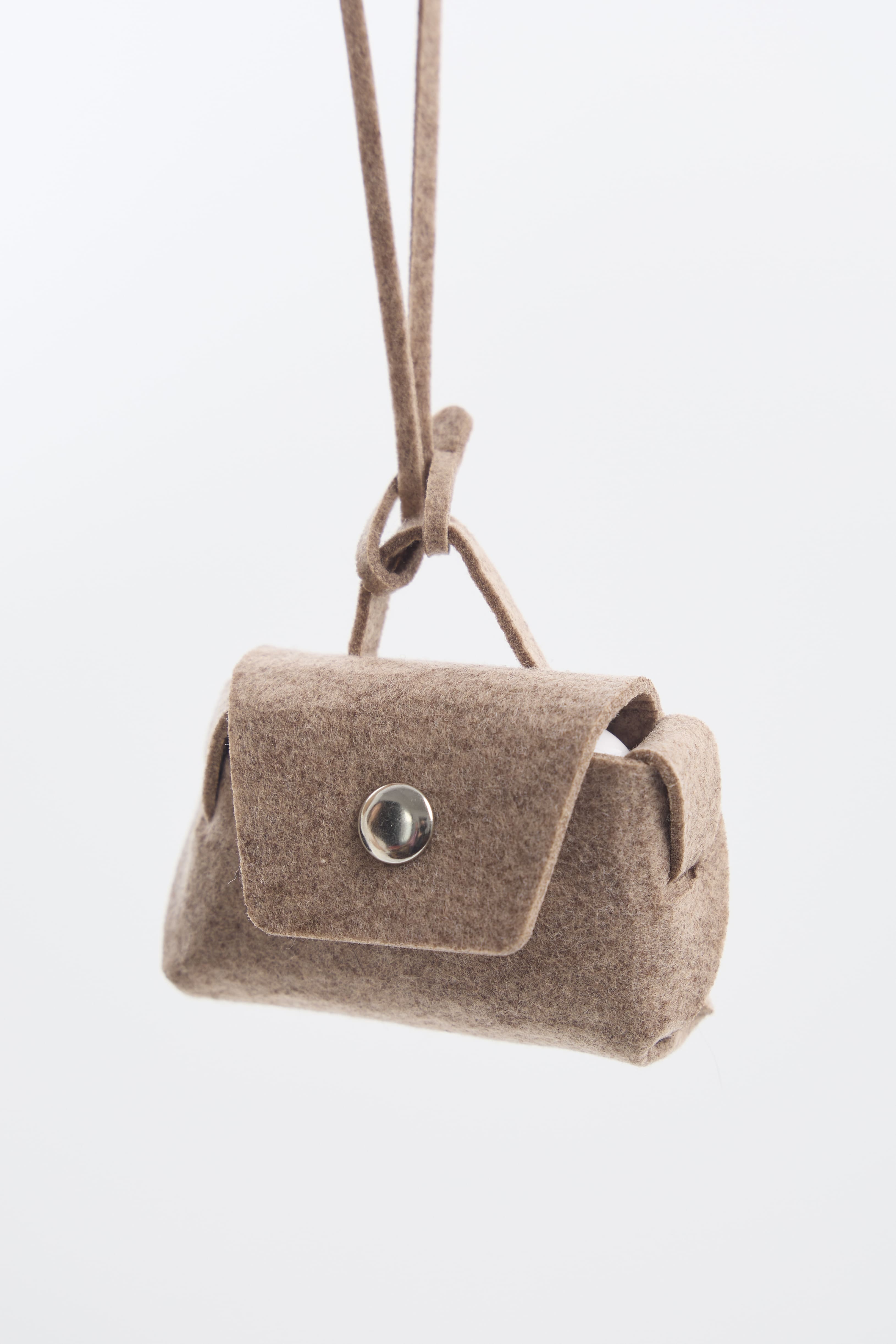 Beige felt mini pouch with a silver clasp on a white background