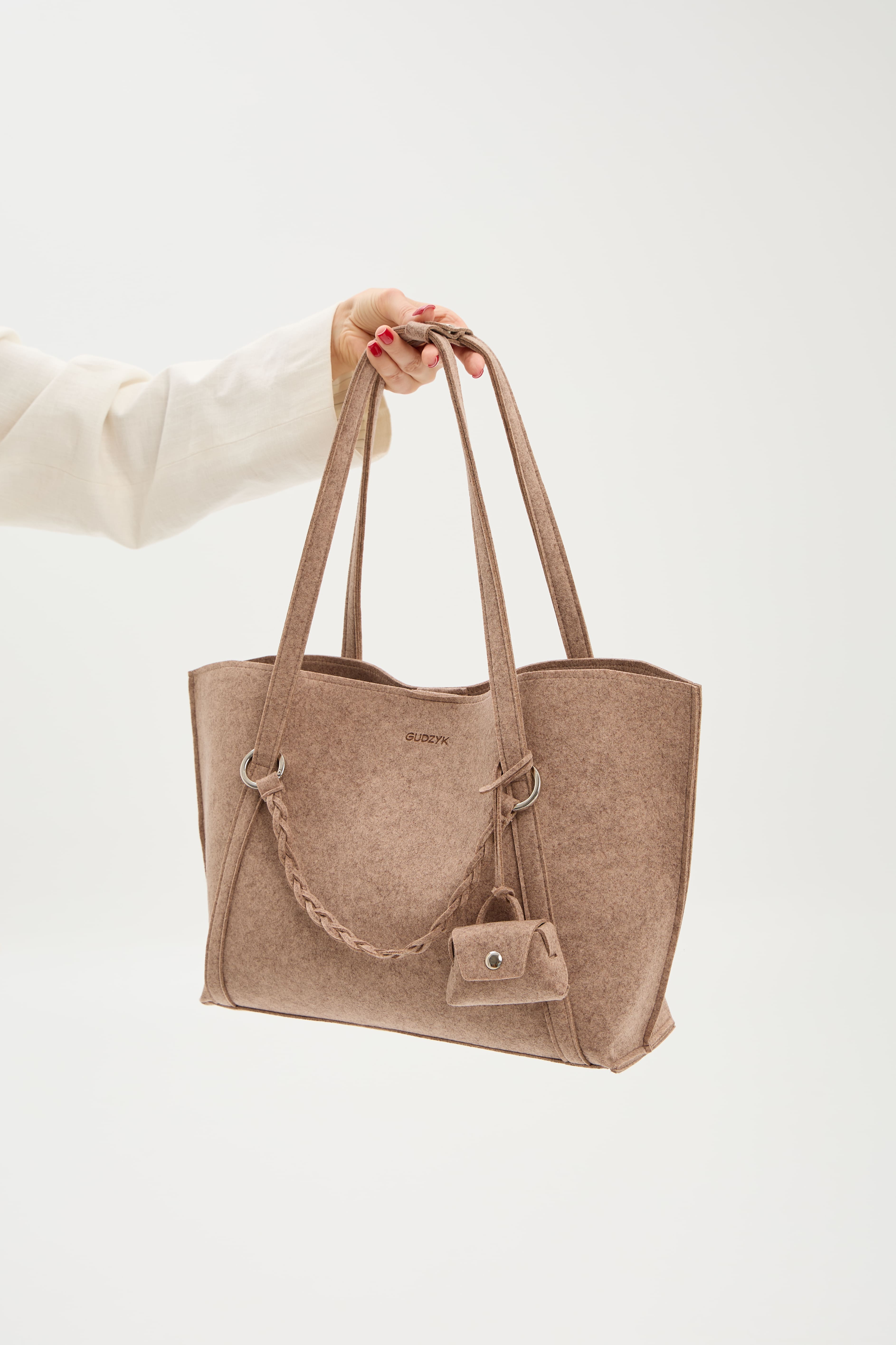 Beige tote bag held by a person on a white background