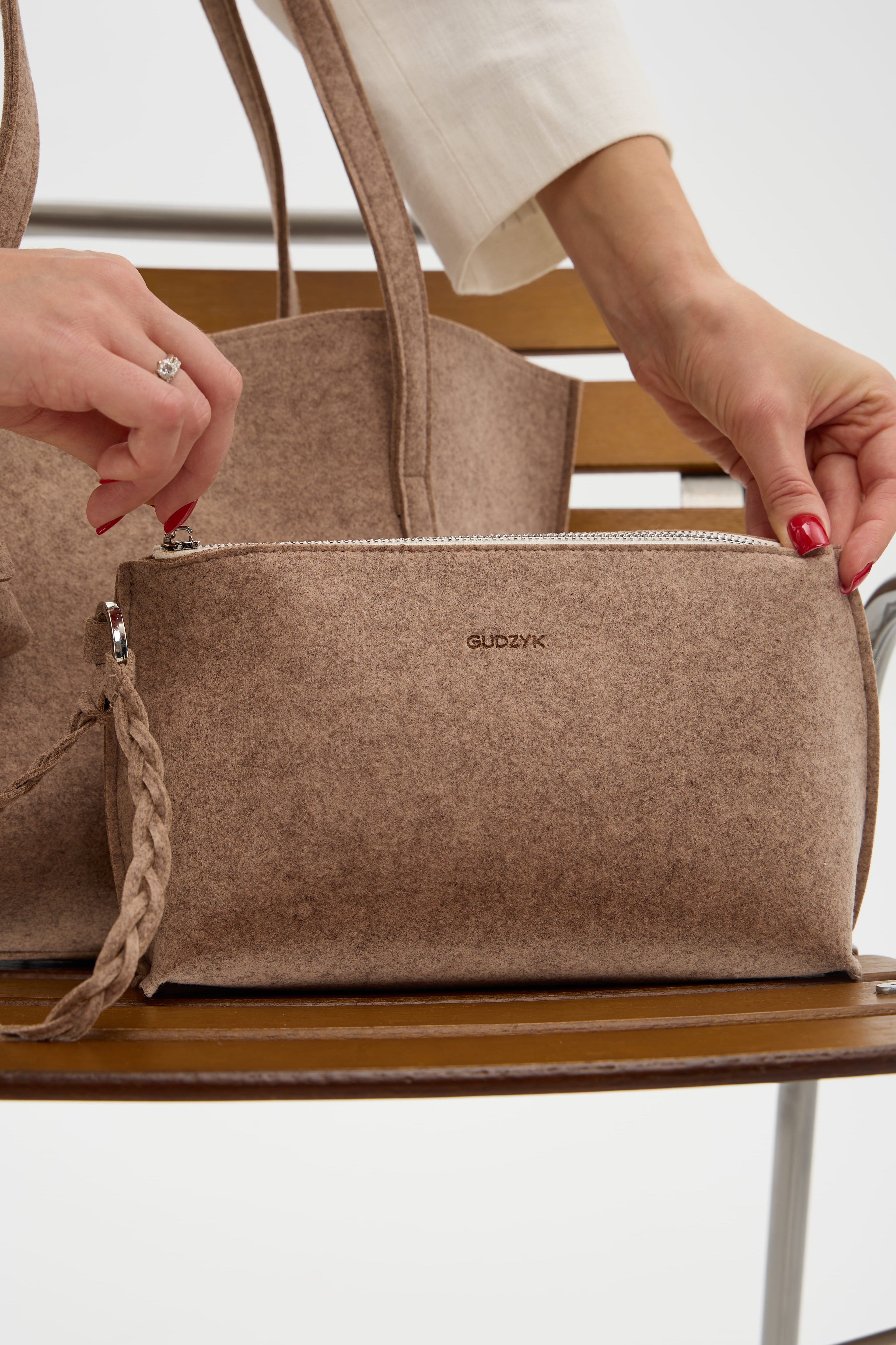 Beige makeup bag with a visible brand logo on a wooden surface.