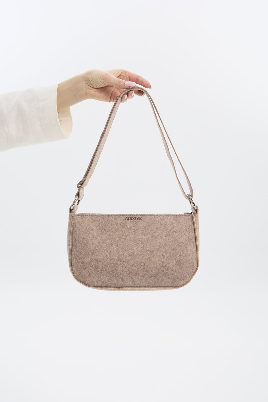 Beige handbag held by a person against a white background