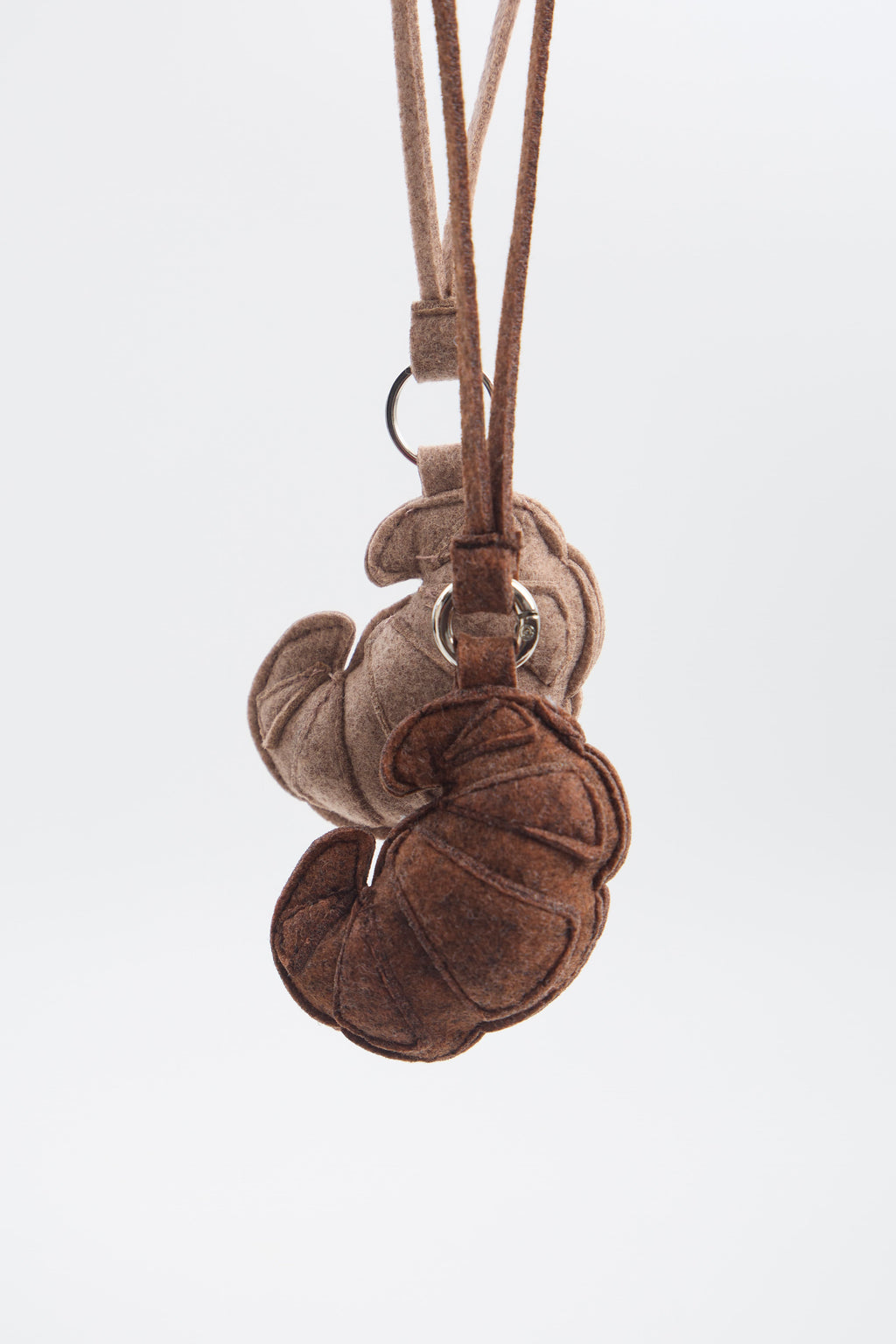 Brown and beige felt keychains with a strap on a white background