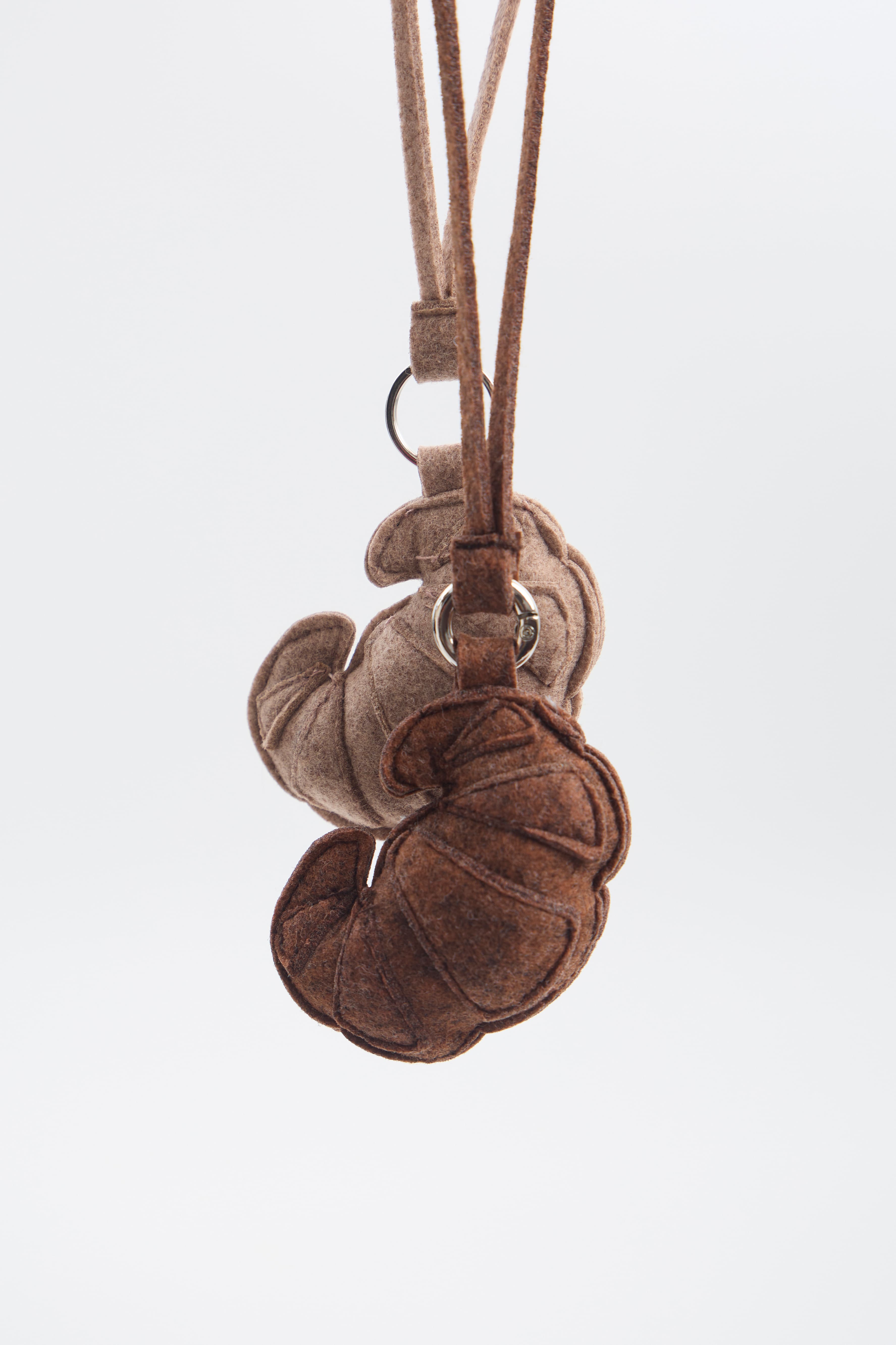 Brown and beige felt keychains with a strap on a white background