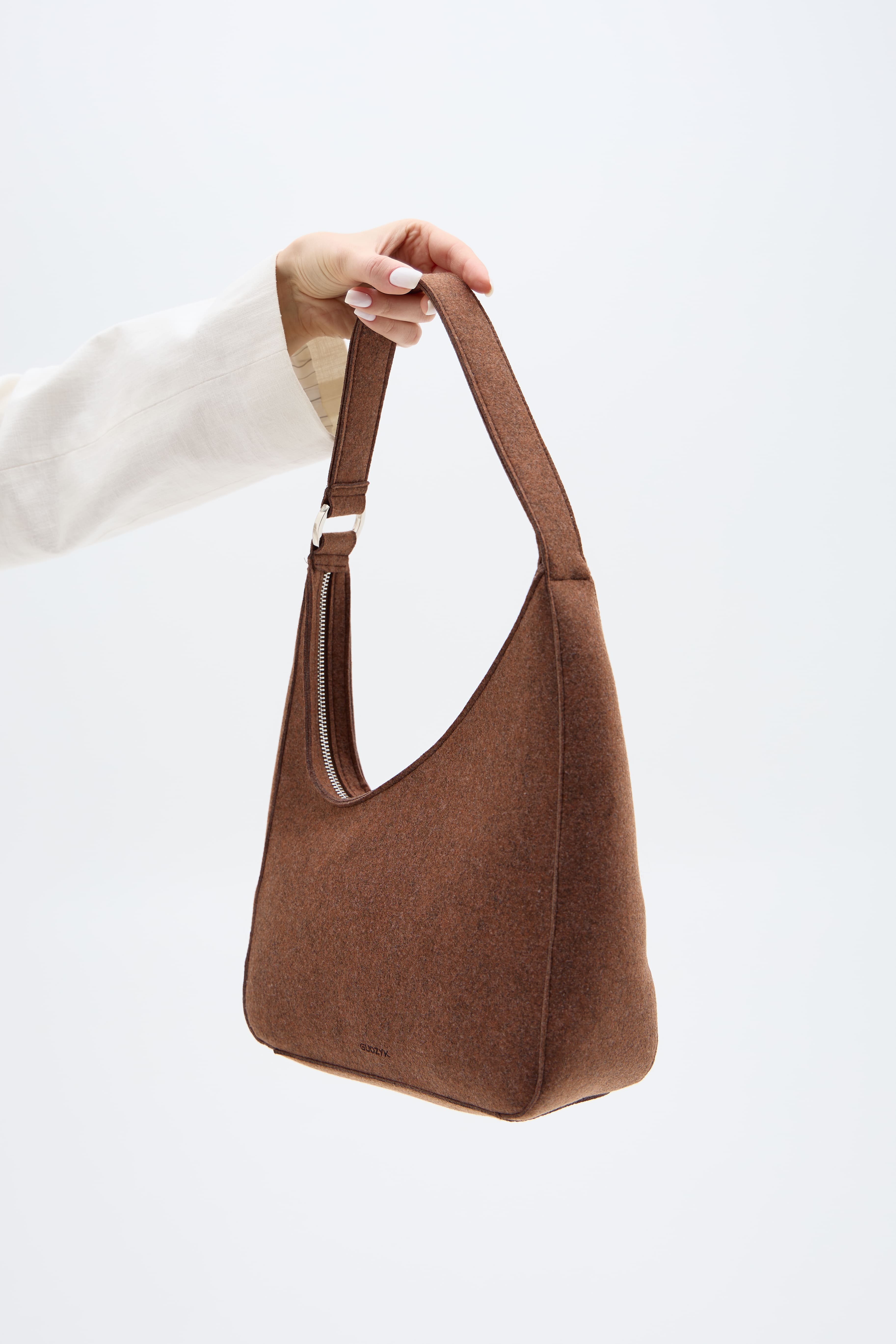 Brown handbag held by a person against a white background