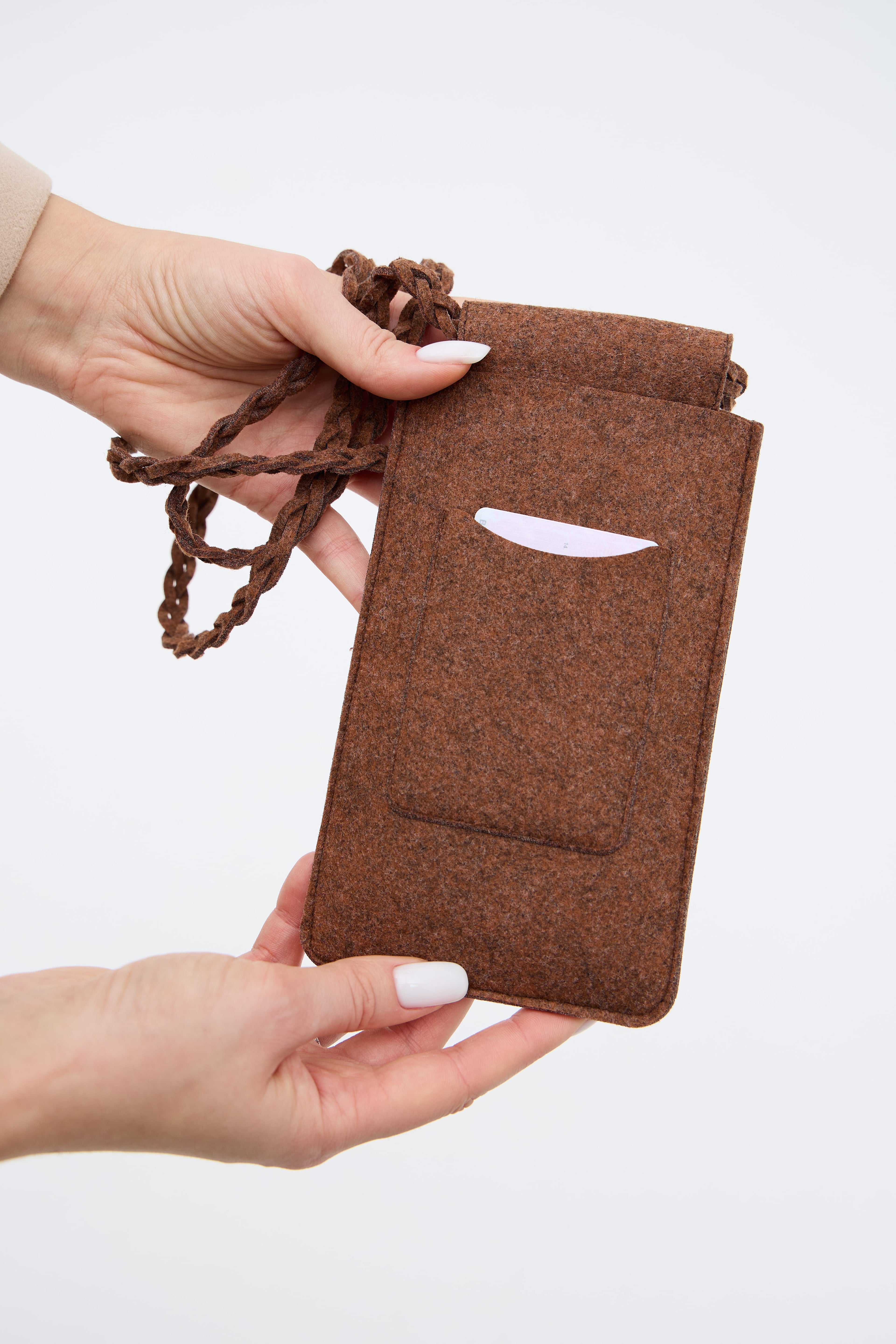 Brown felt bag with drawstring held by a hand on a white background