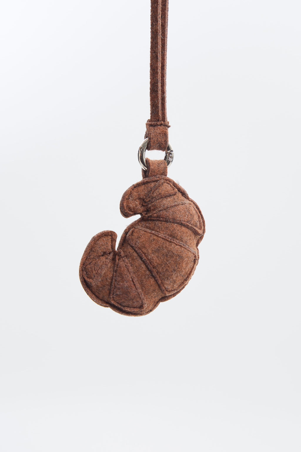 Brown felt croissant keychain on a white background