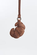 Brown felt croissant keychain on a white background