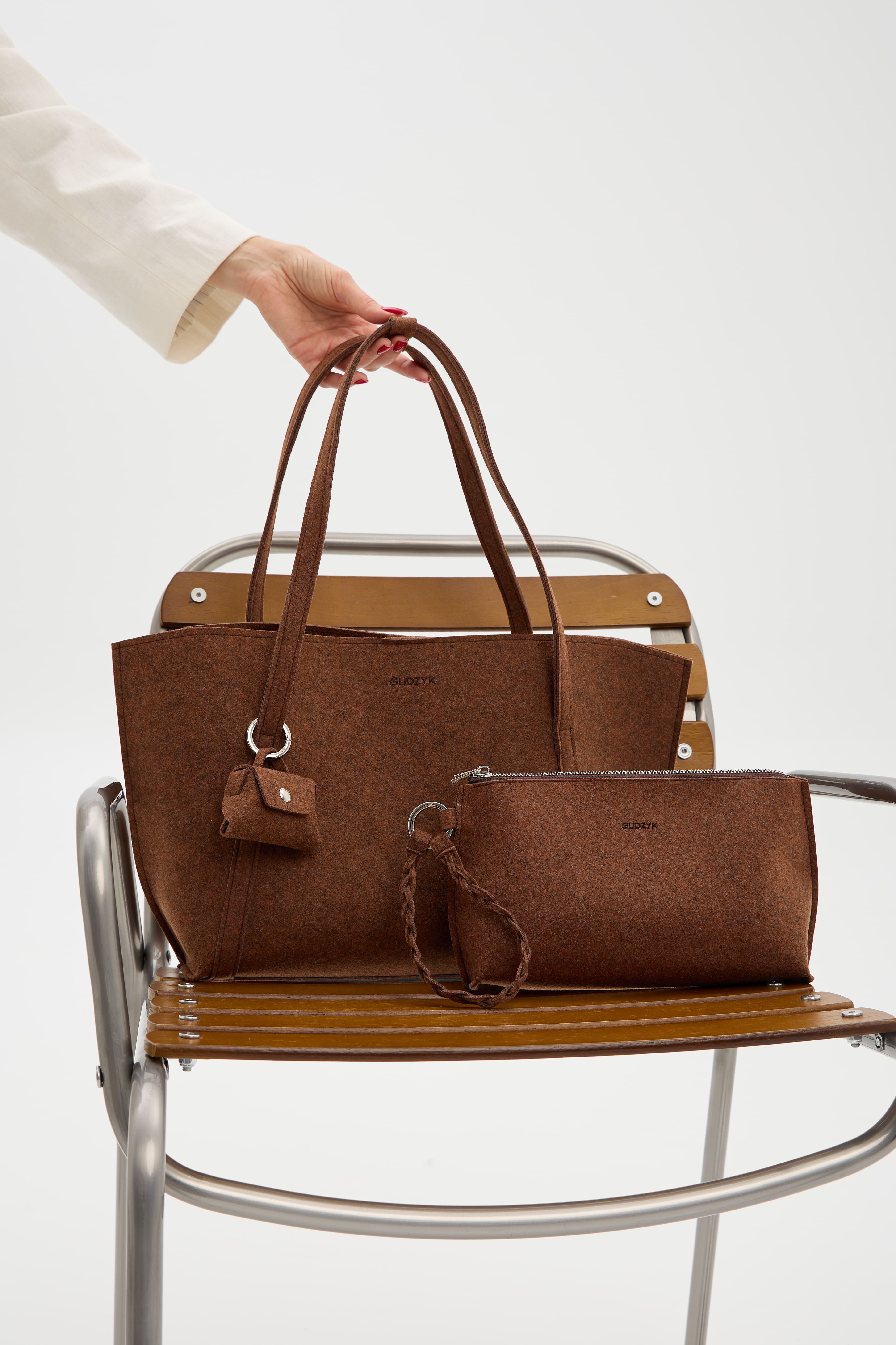 Brown handbag and pouch on a chair with a white background