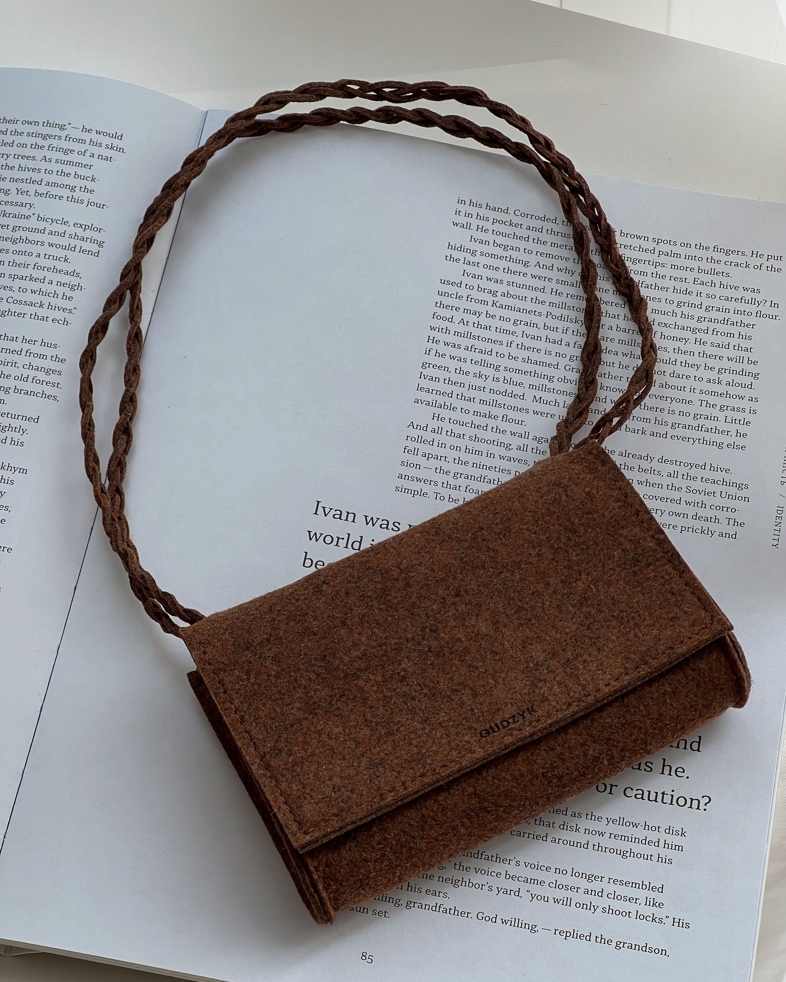 Brown felt handbag with a braided handle on an open book