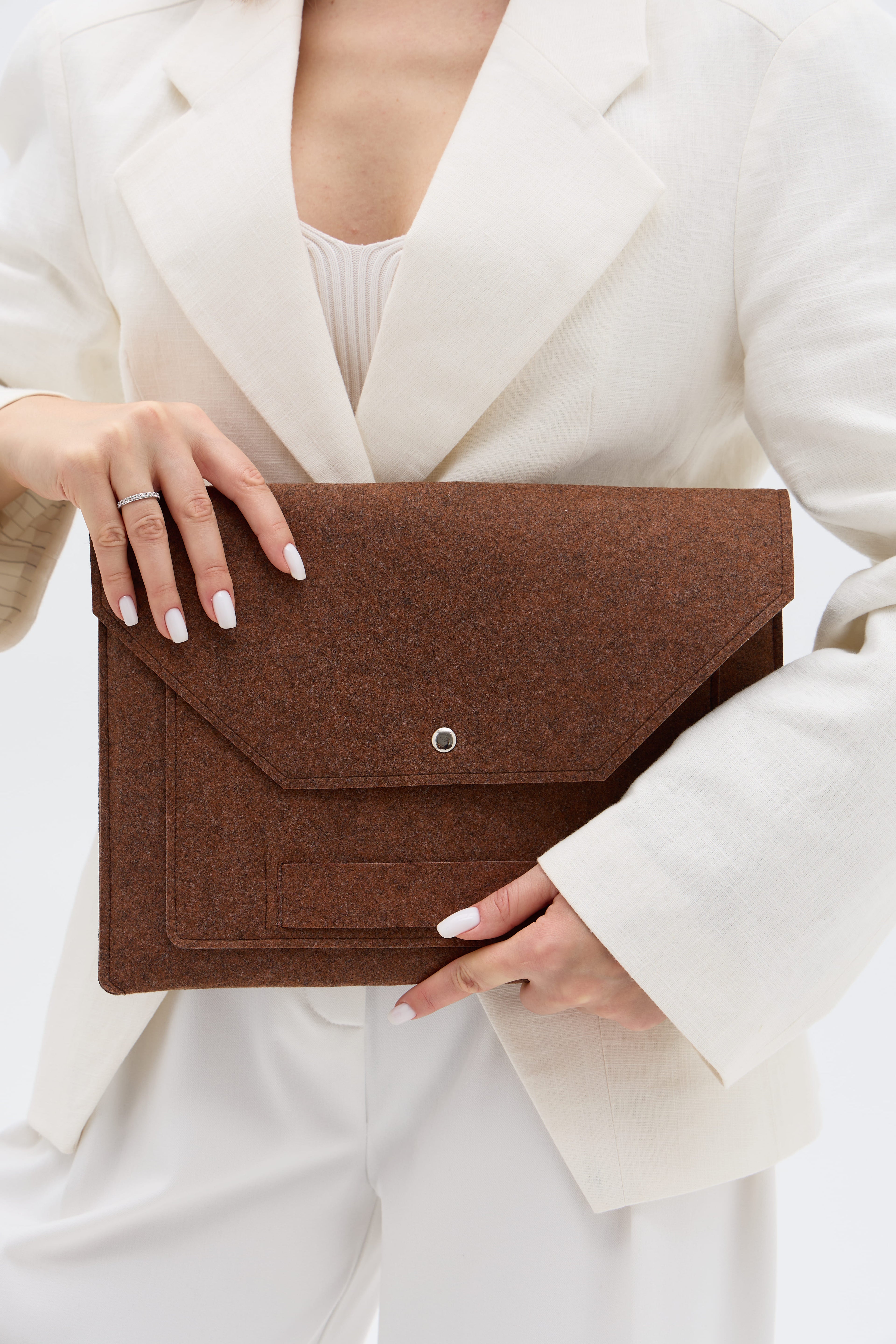 Brown case held by a person wearing a white outfit on a light background