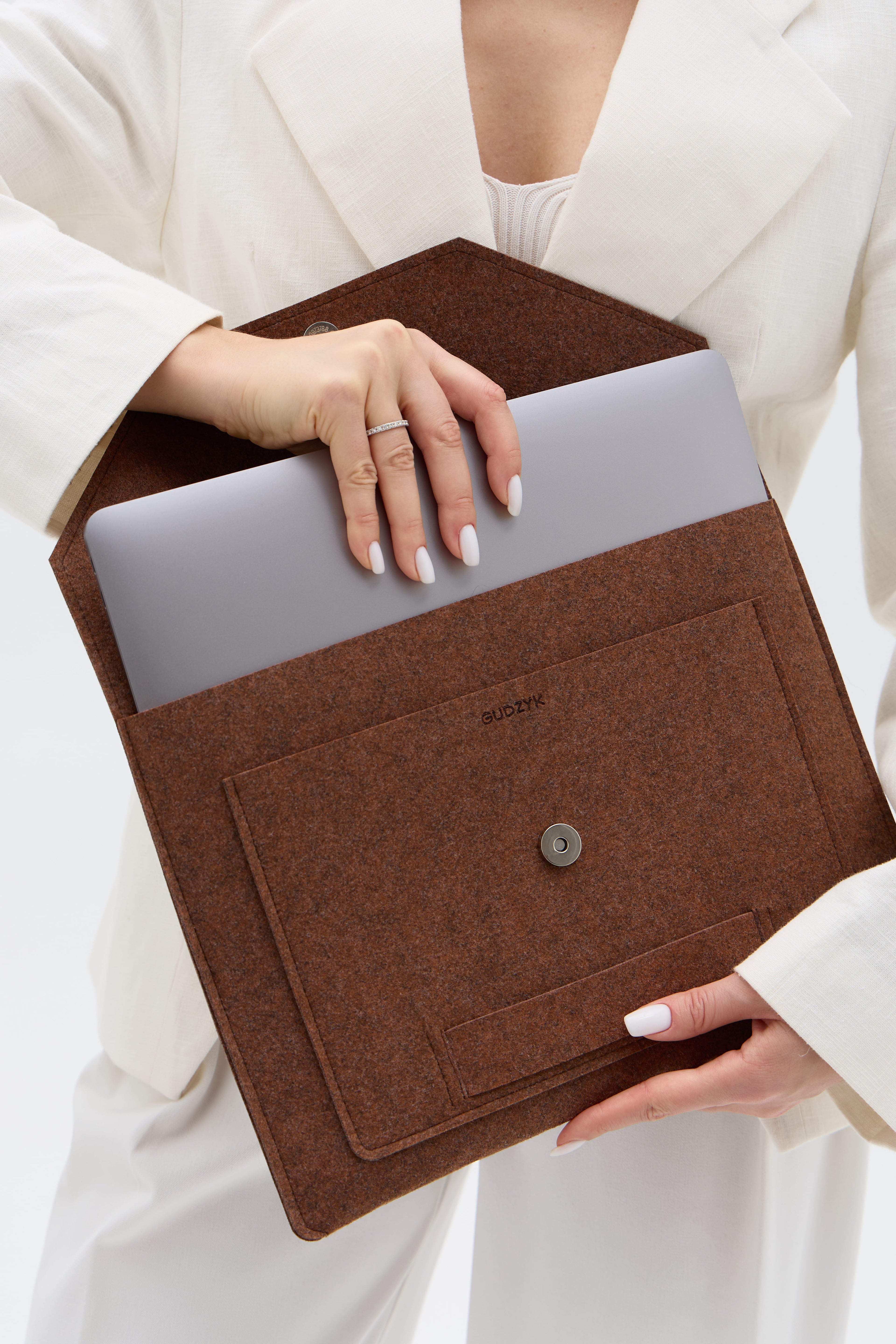 Brown laptop sleeve held by a person wearing a white outfit