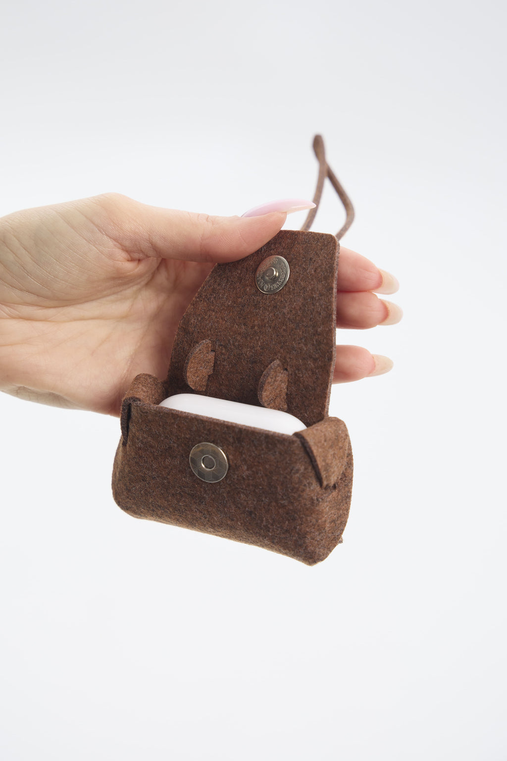 Brown felt case with a button closure held by a hand on a white background