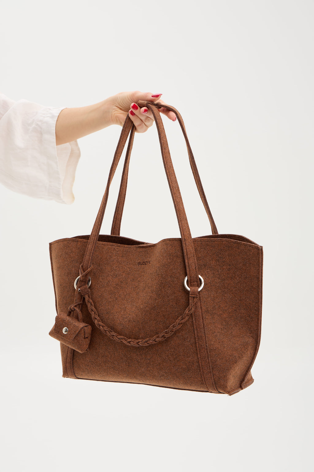 Brown tote bag held by a person on a white background