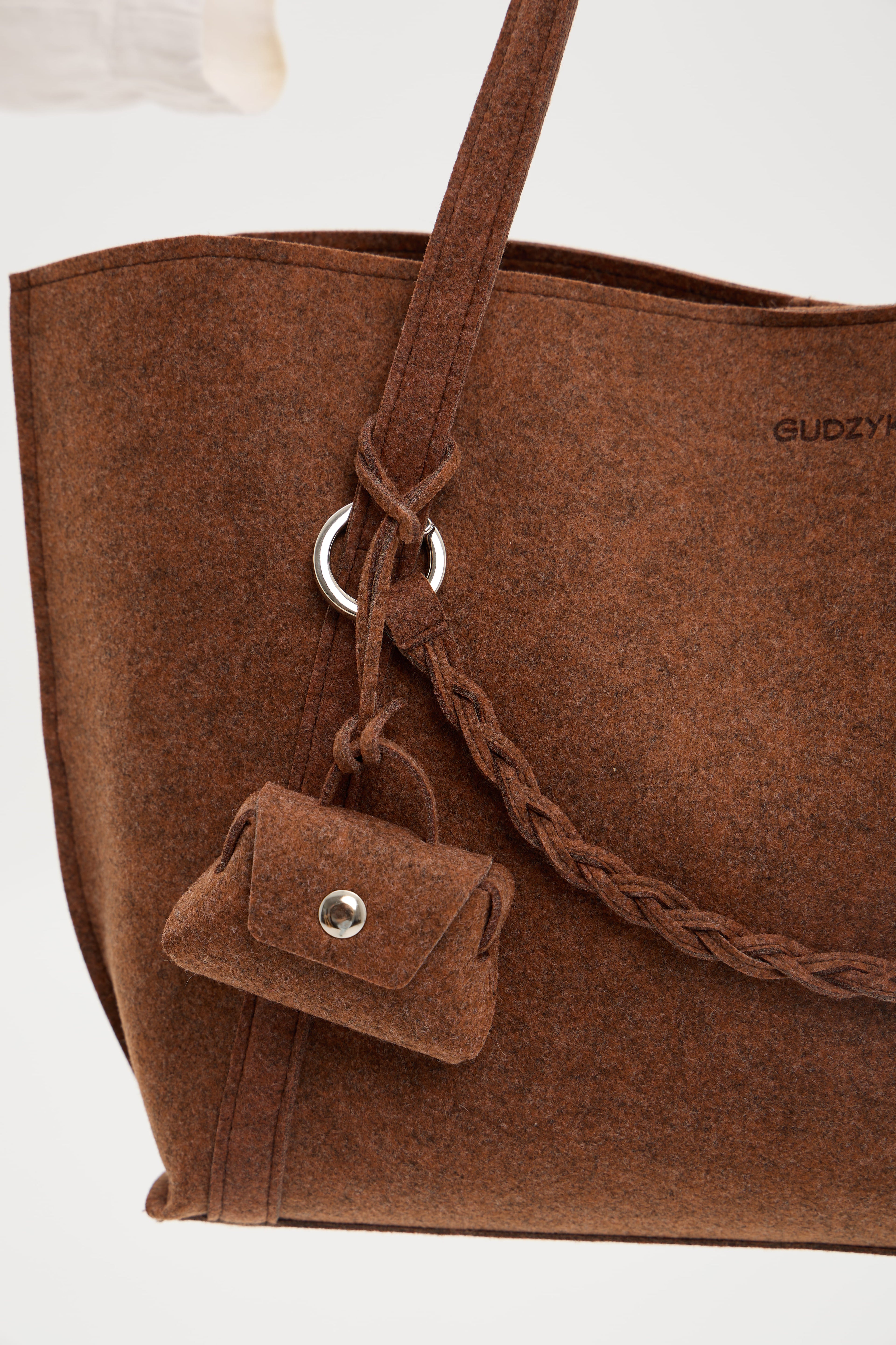 Brown tote bag with a small pouch attached to the handle on a white background