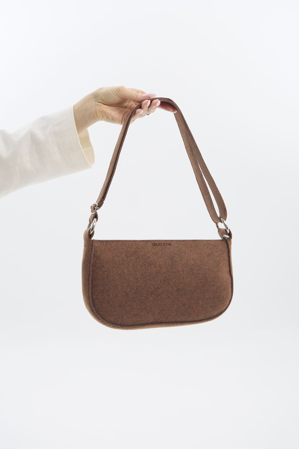 Brown shoulder bag held by a hand on a white background