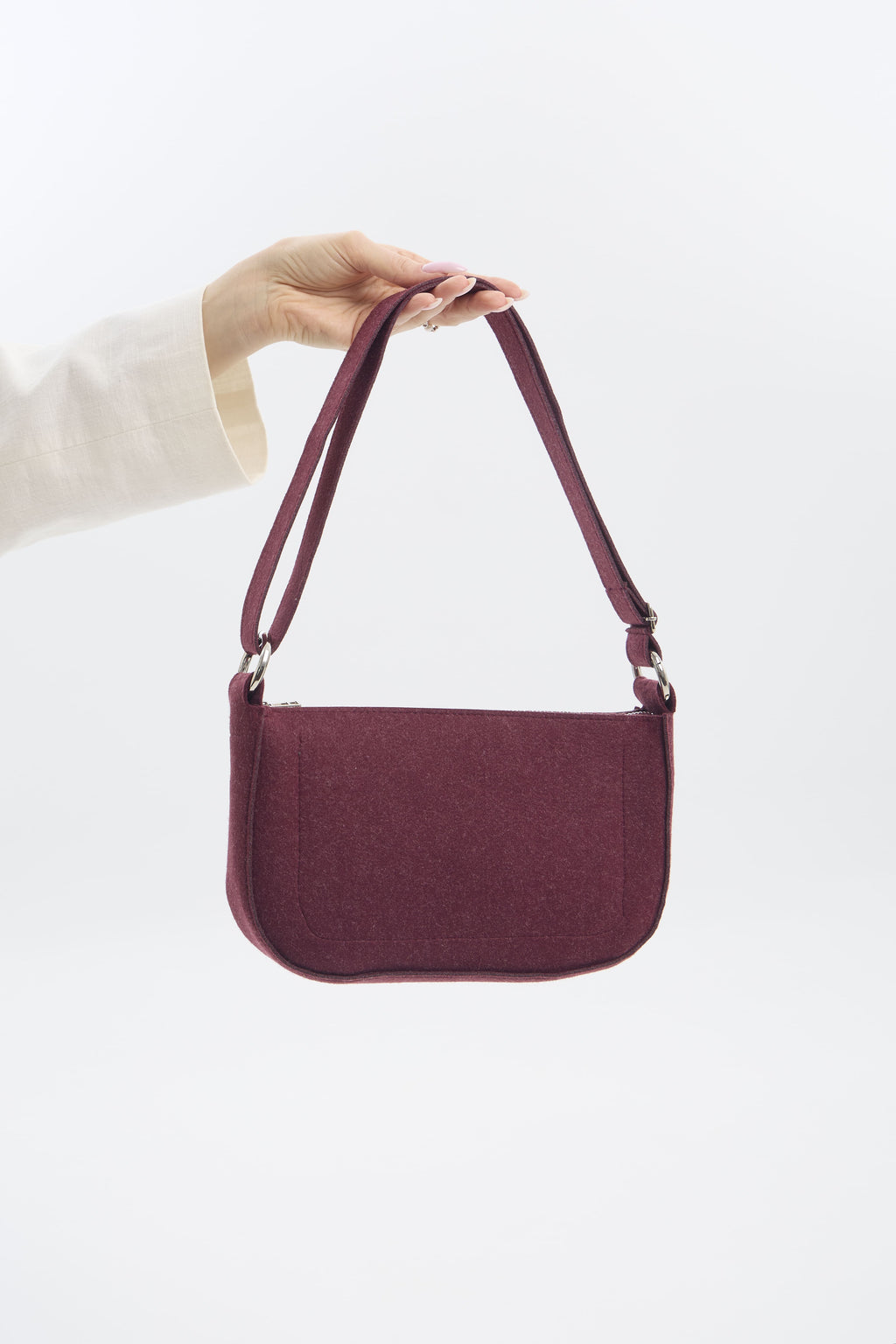 Burgundy handbag held by a person against a white background