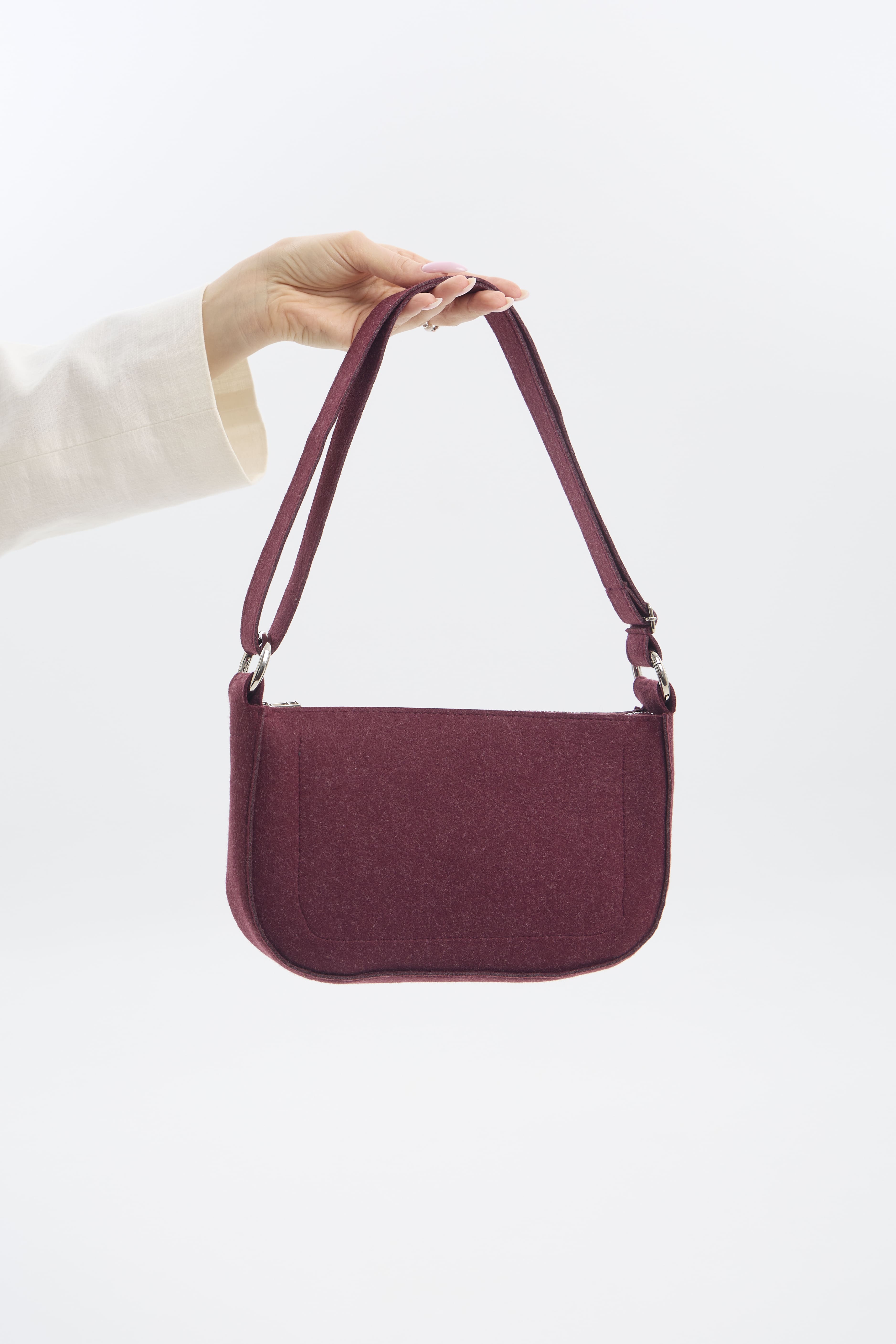 Burgundy handbag held by a person against a white background