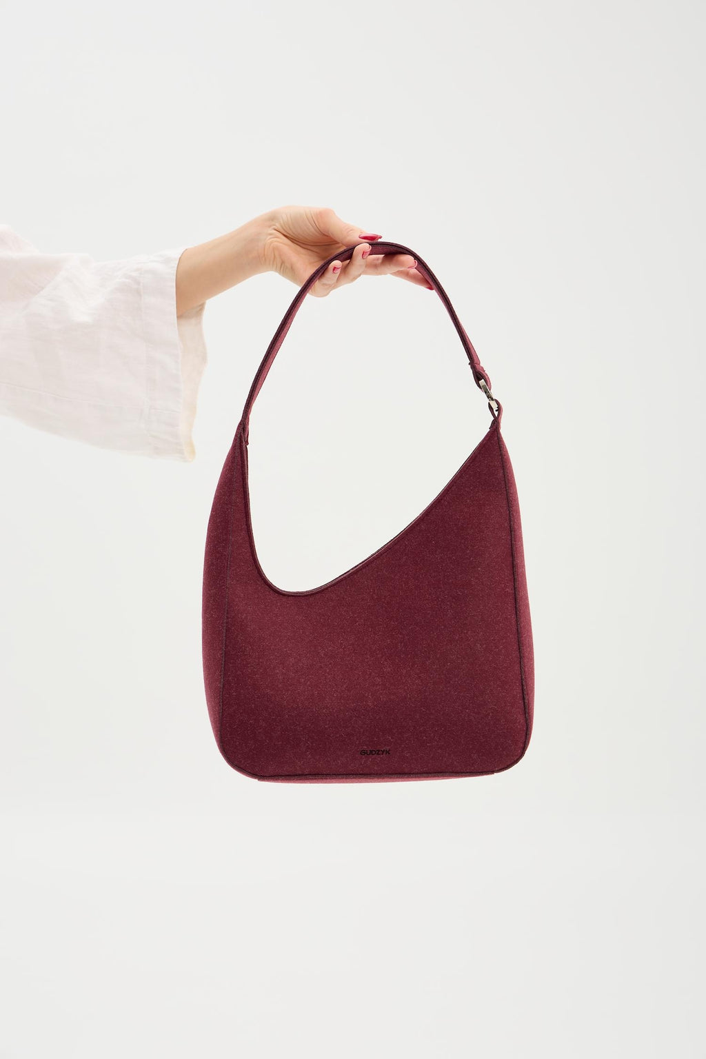 Burgundy handbag held by a person against a white background