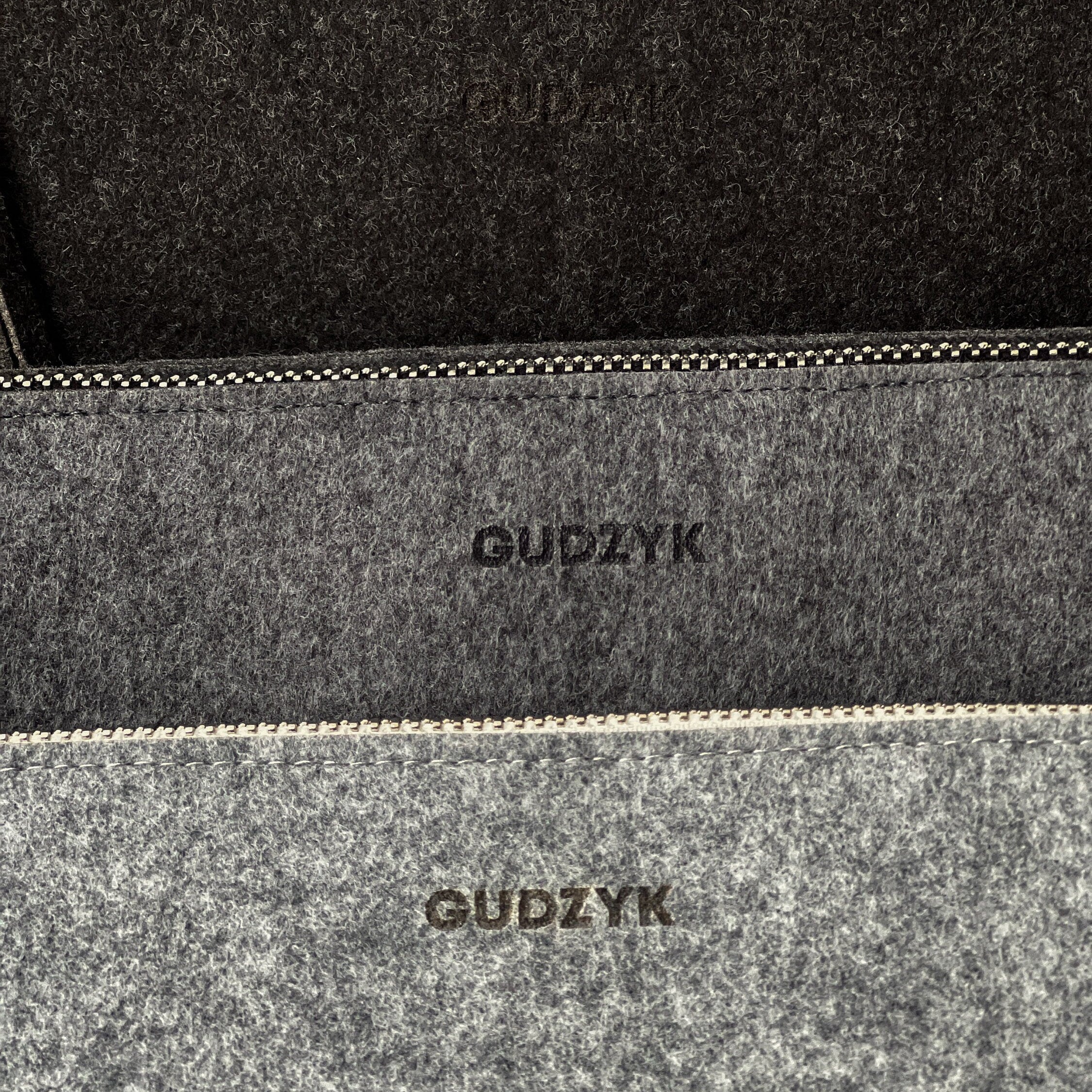 Close-up of a gray felt pouch with 'GUDZYK' branding.