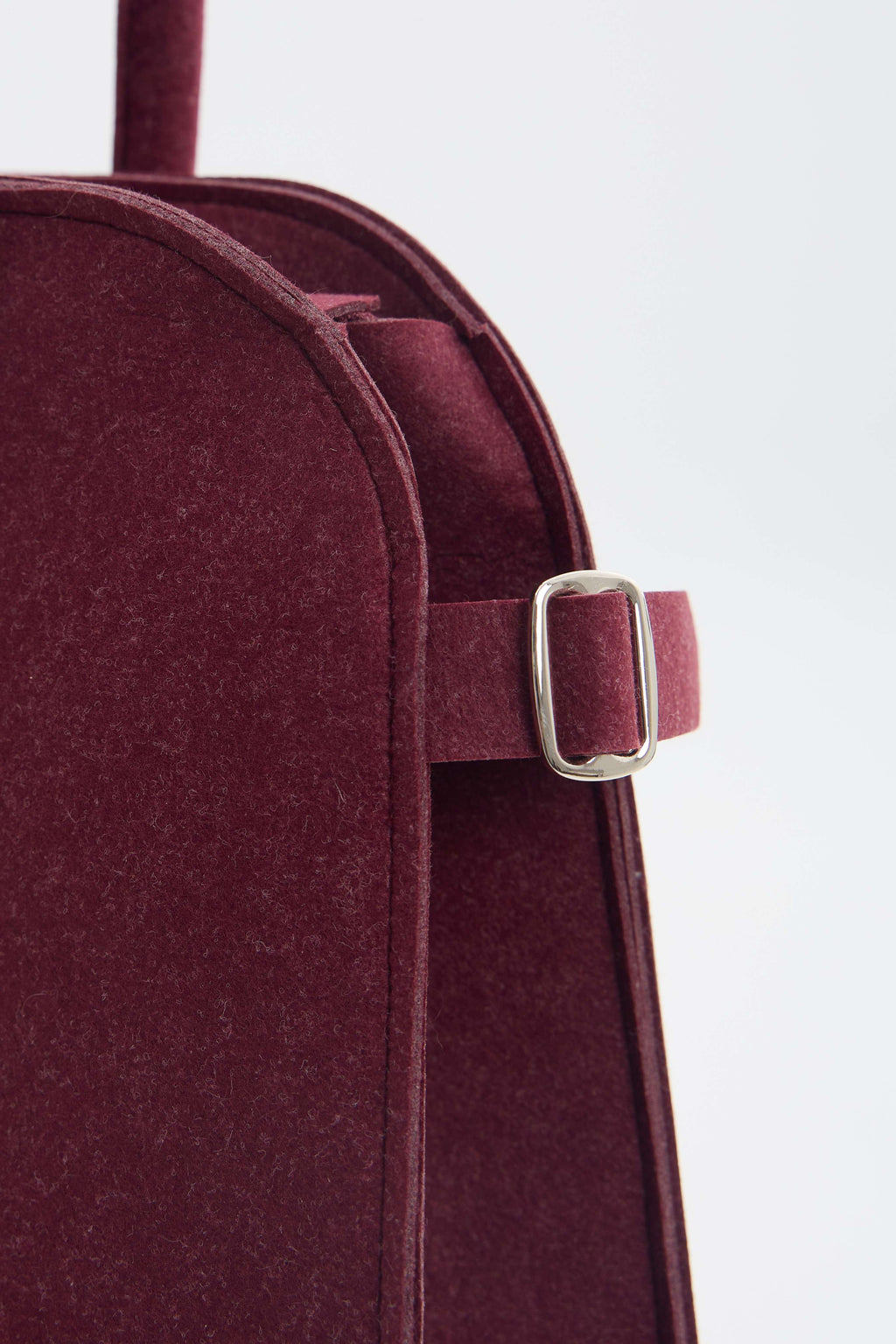 Close-up of a burgundy ecofelt bag with a silver buckle on a white background
