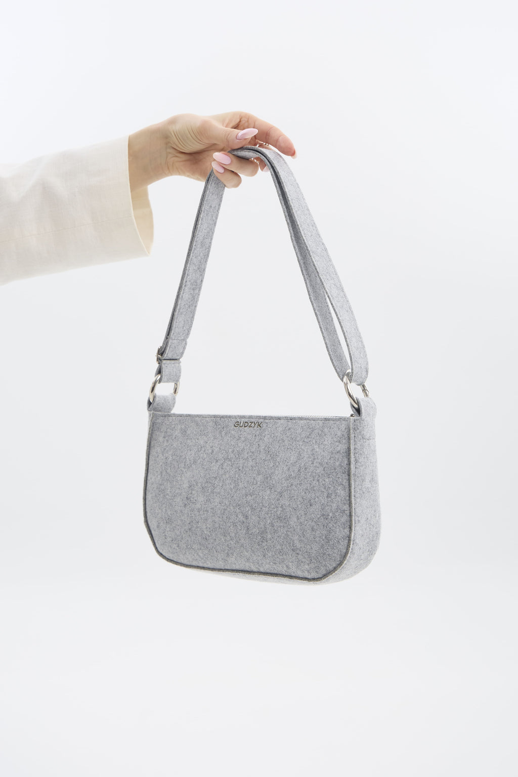 Gray shoulder bag held by a person on a white background