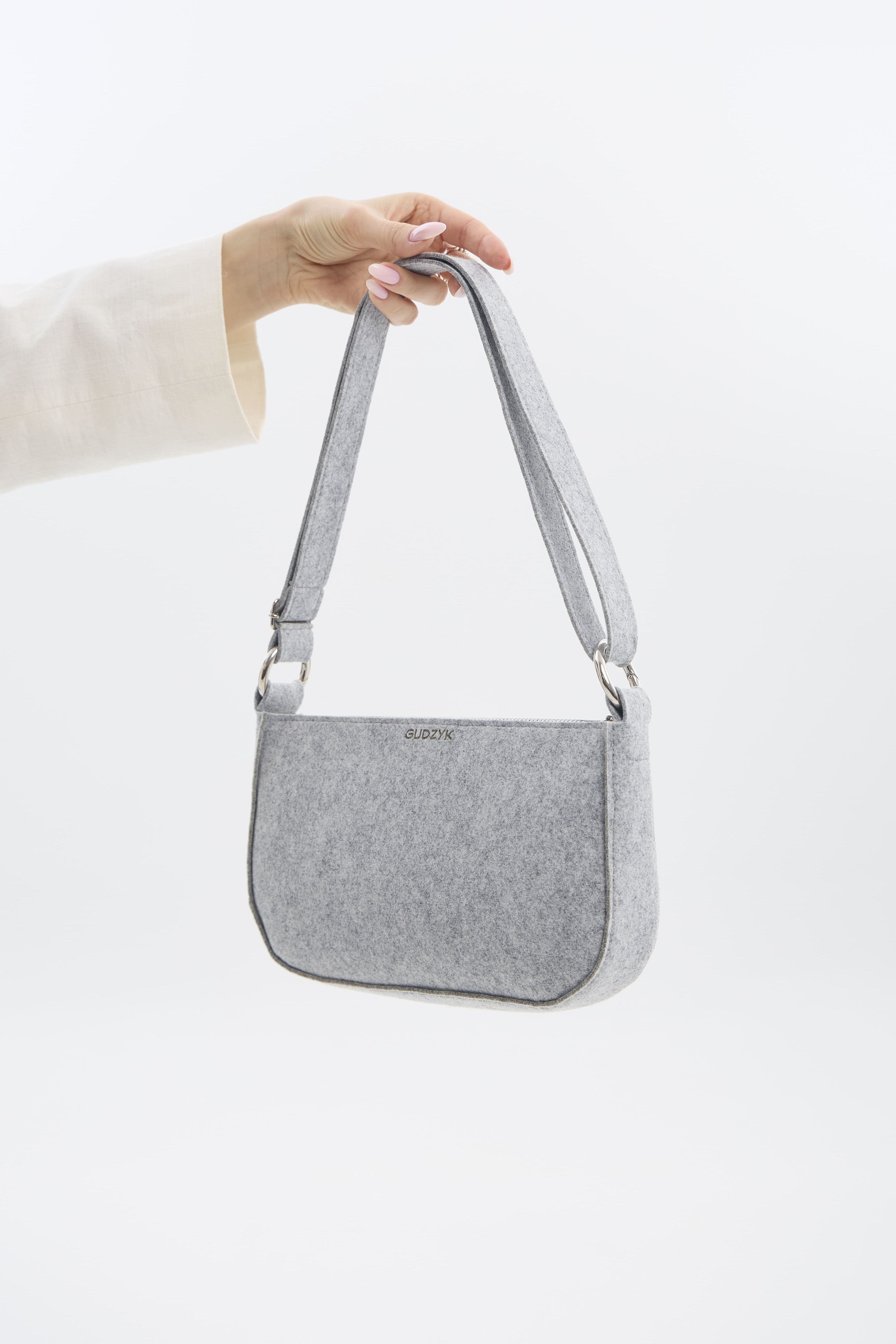 Gray shoulder bag held by a person on a white background