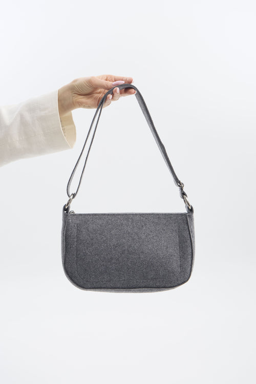 Gray shoulder bag held by a person against a white background