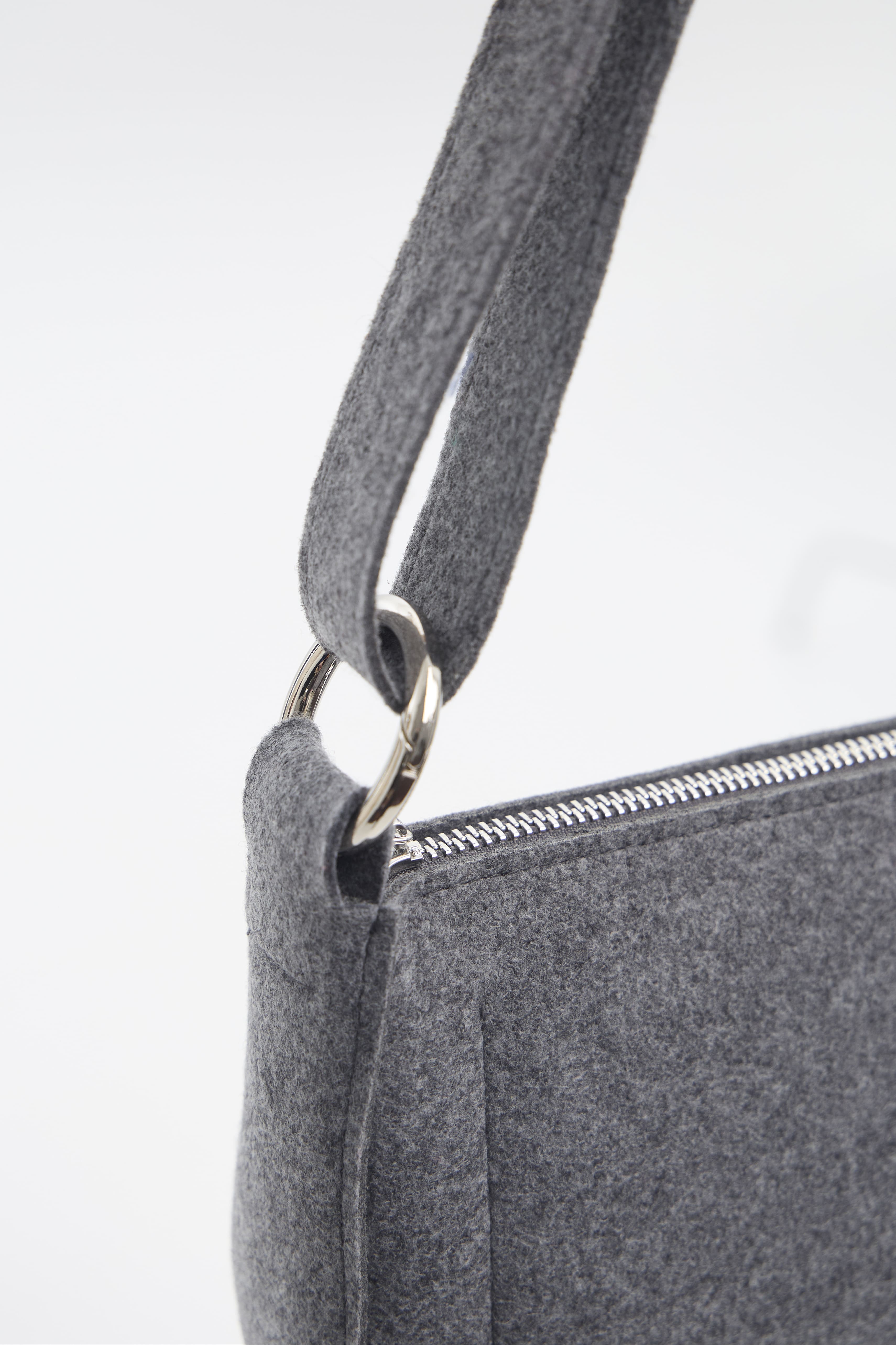 Gray crossbody bag with a zipper on a white background
