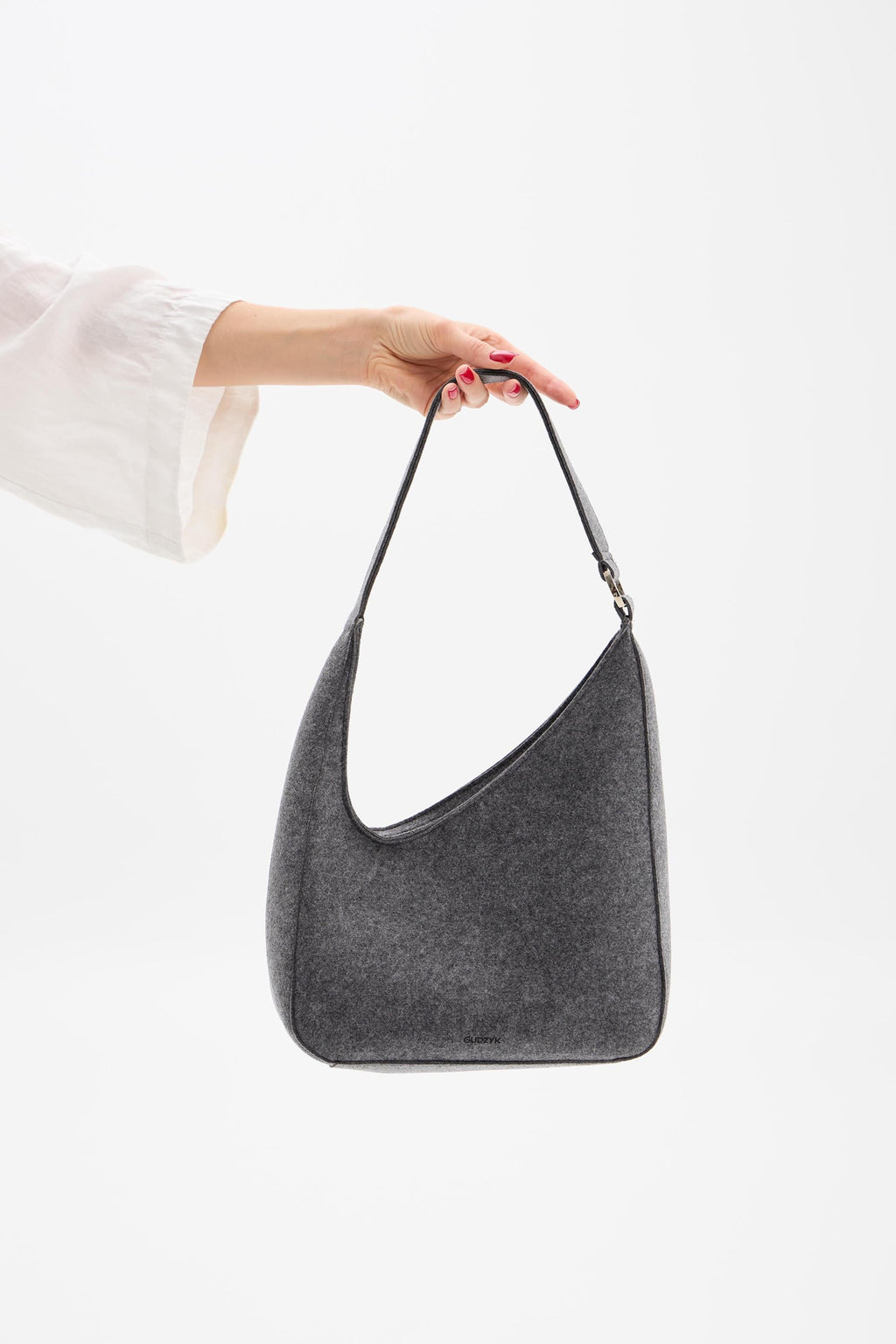 Gray handbag held by a person against a white background