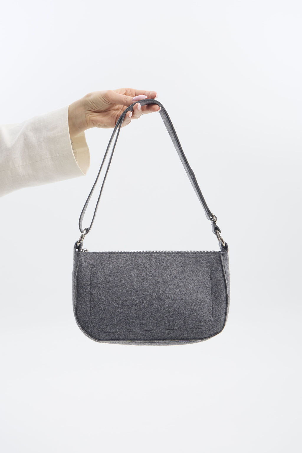Gray shoulder bag held by a person against a white background