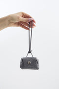 Small gray felt mini pouch with a strap held by a hand on a white background