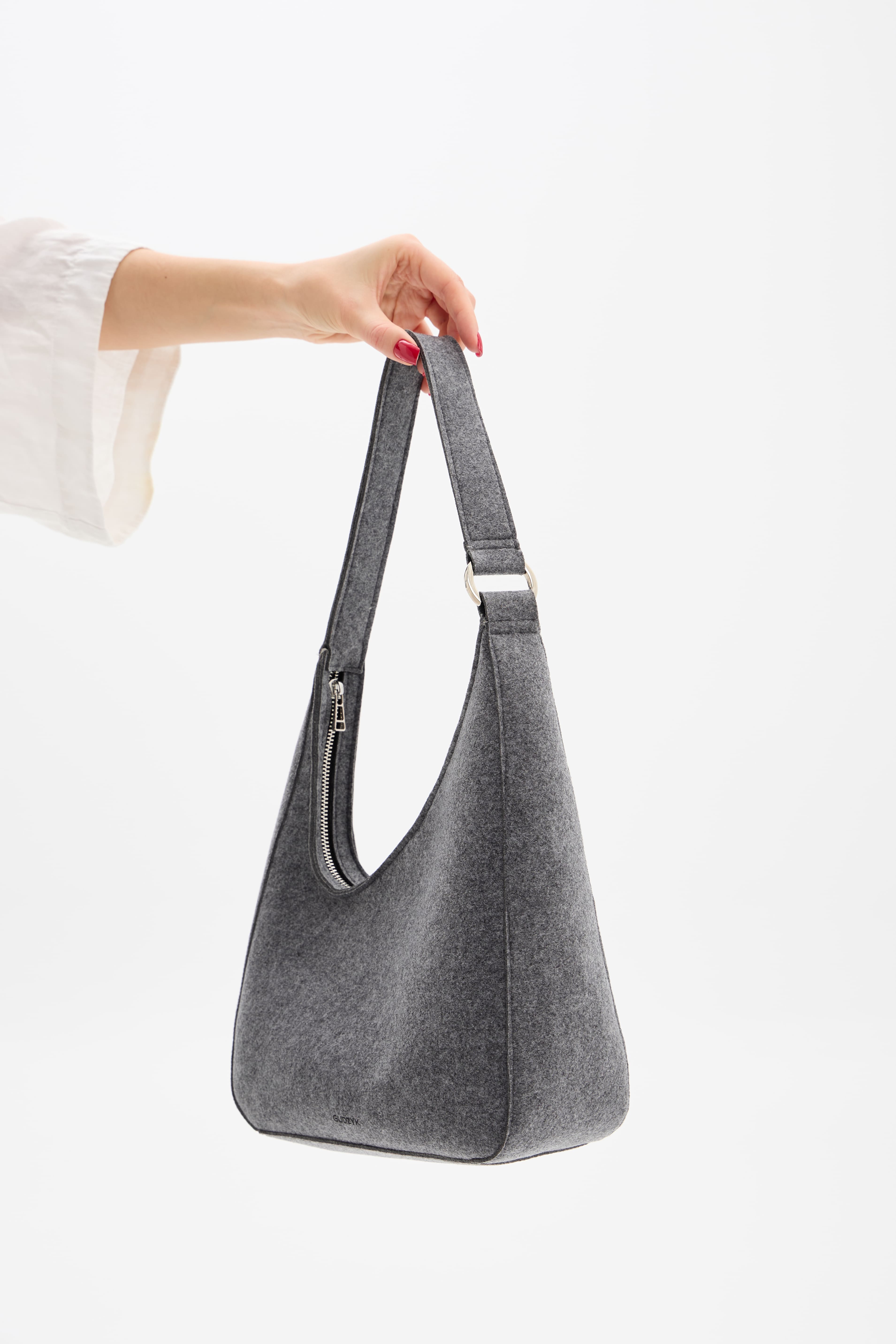 Gray shoulder bag held by a person against a white background