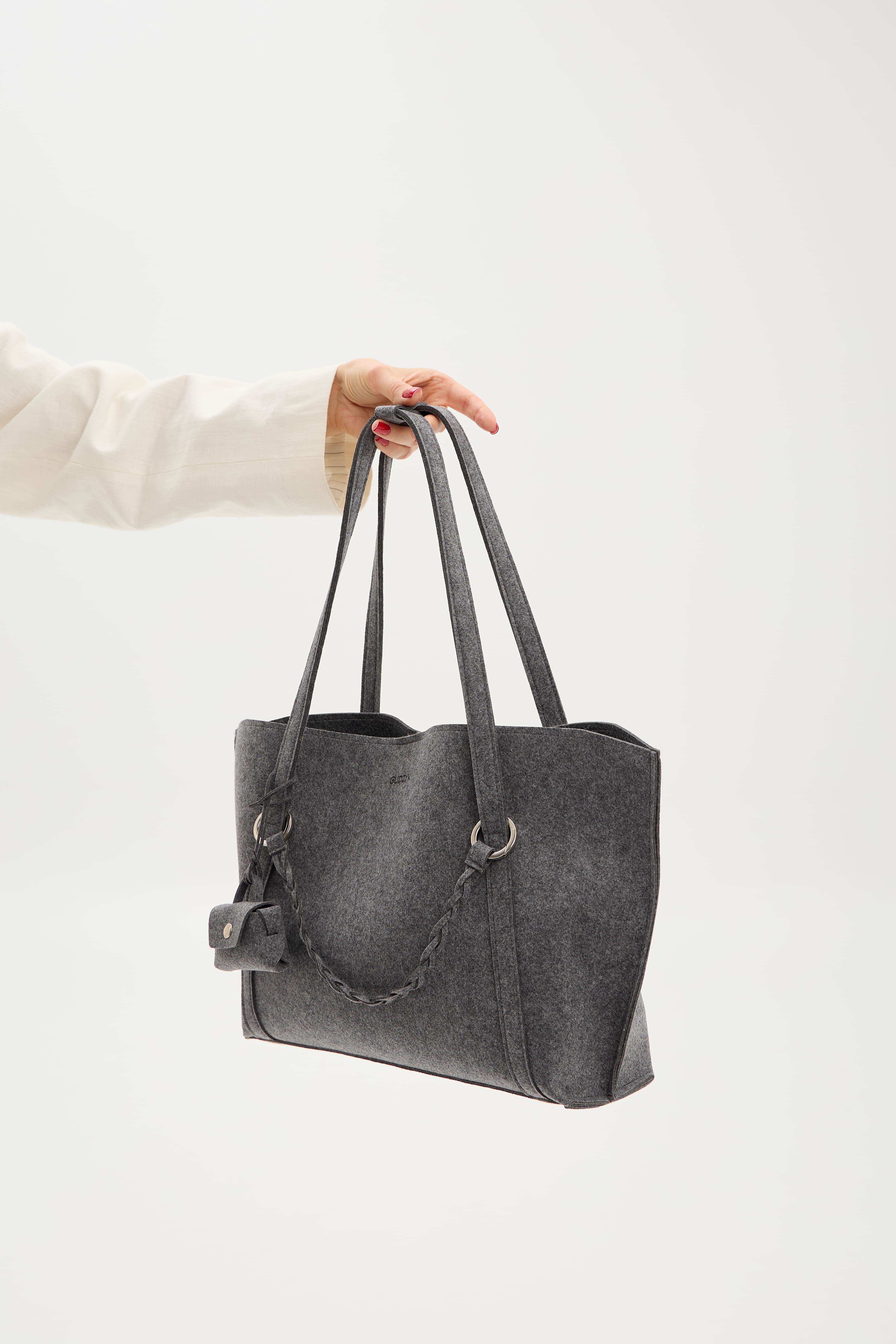 Gray tote bag held by a person against a white background
