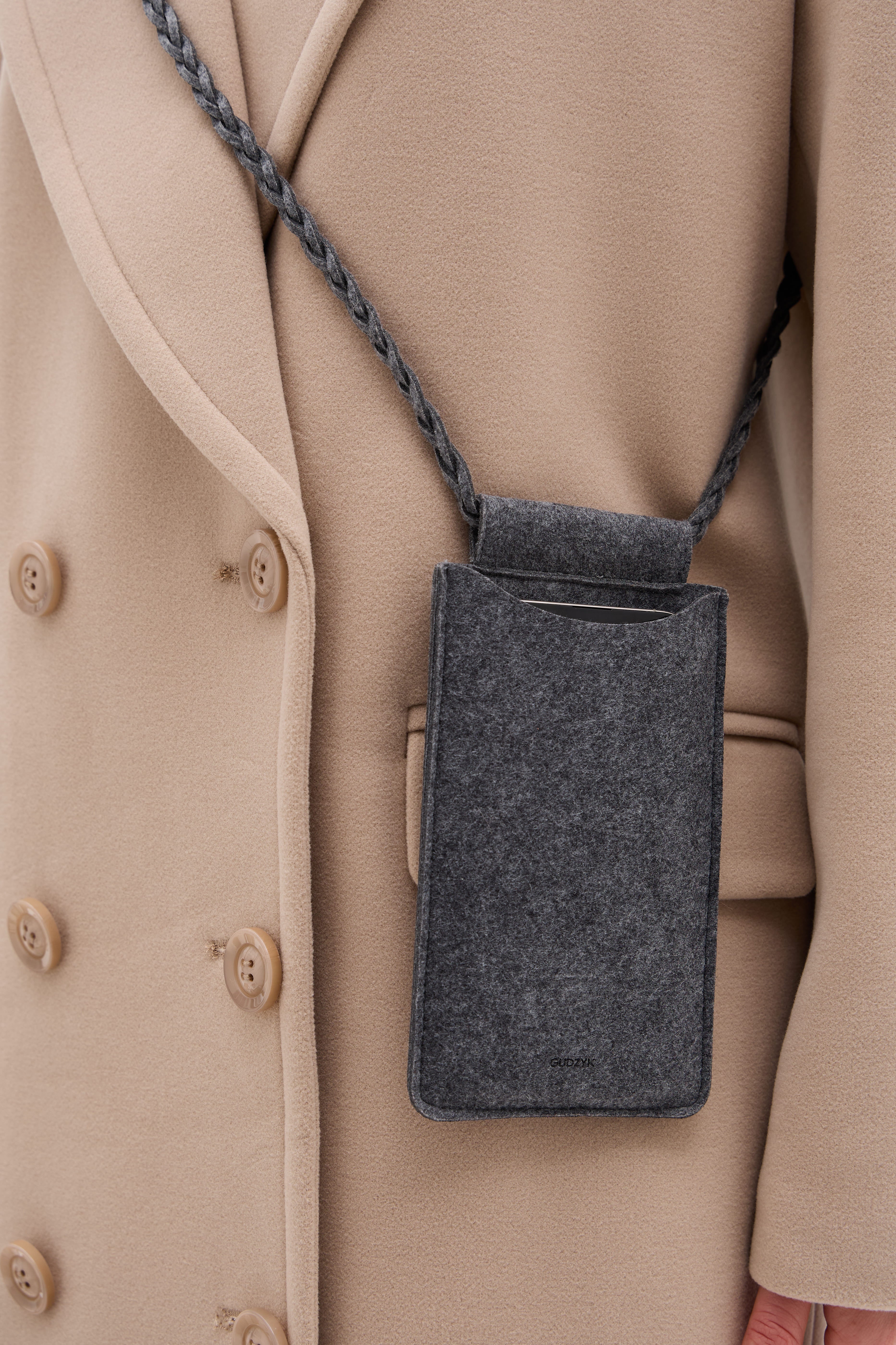 Gray phone pouch hanging from a beige coat