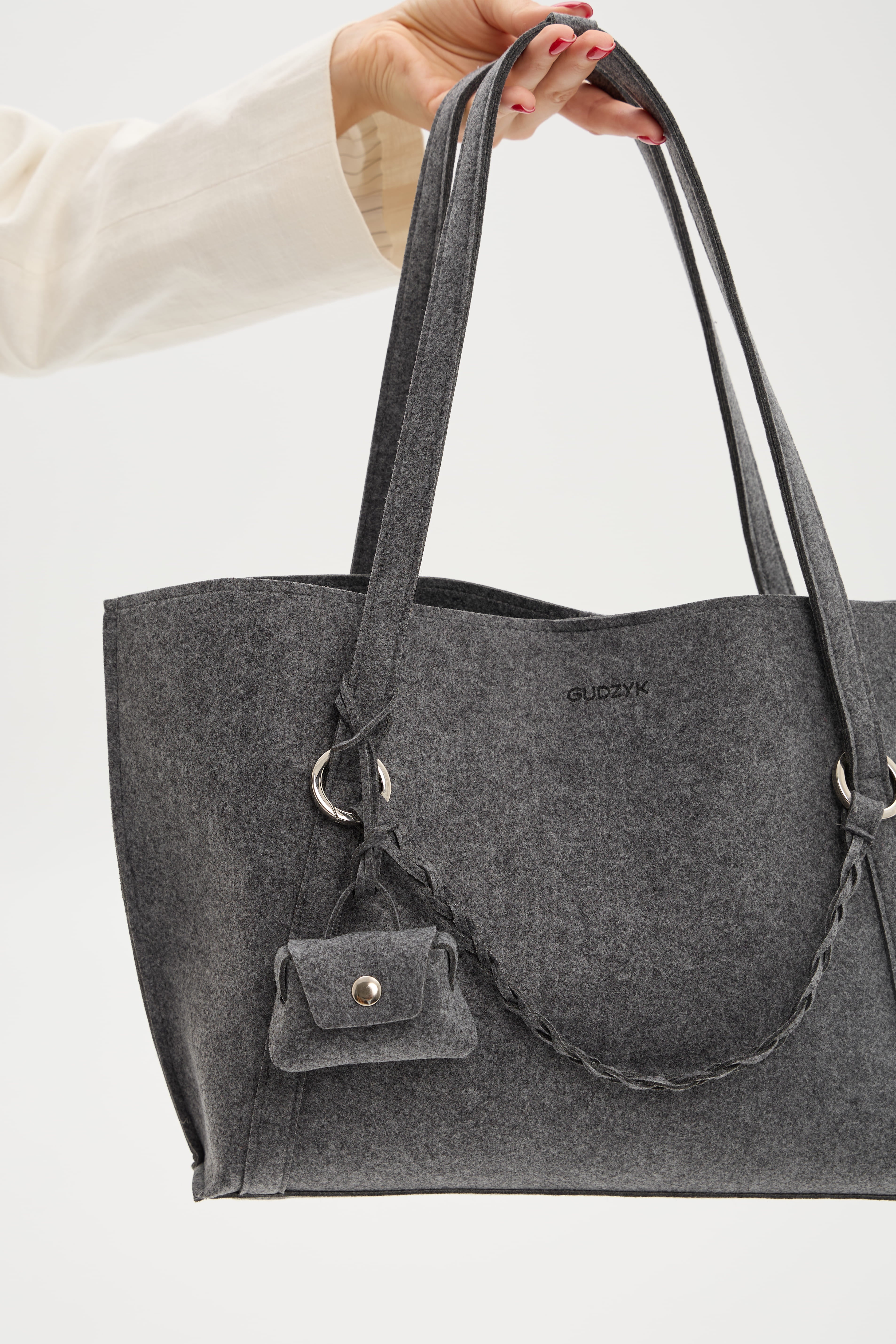 Gray tote bag with a small bag held by a hand on a white background