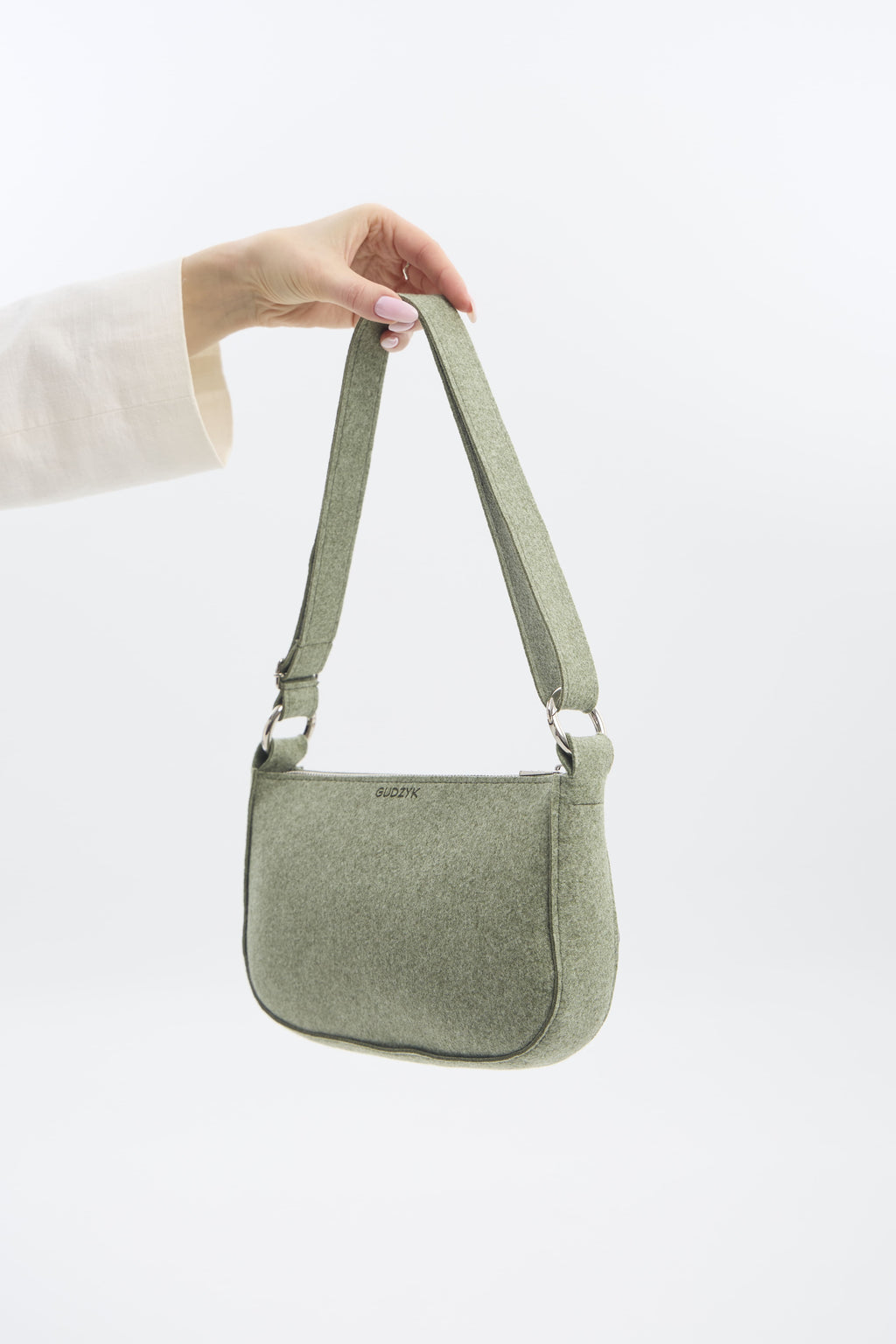 Green shoulder bag held by a person on a white background