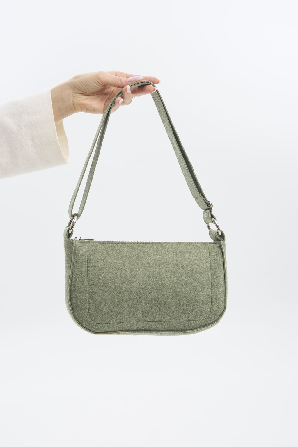 Green shoulder bag held by a hand on a white background