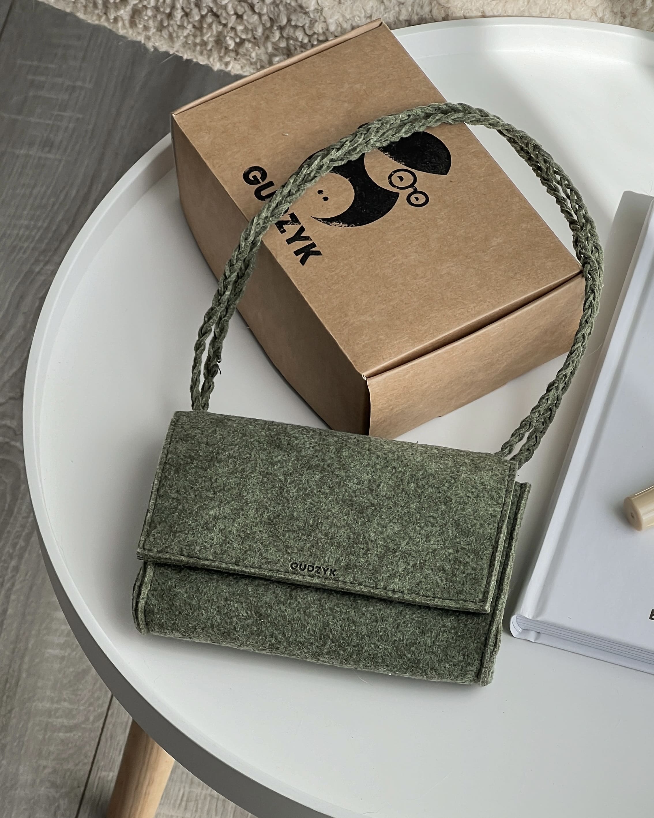 Green handbag with a brown box on a white surface