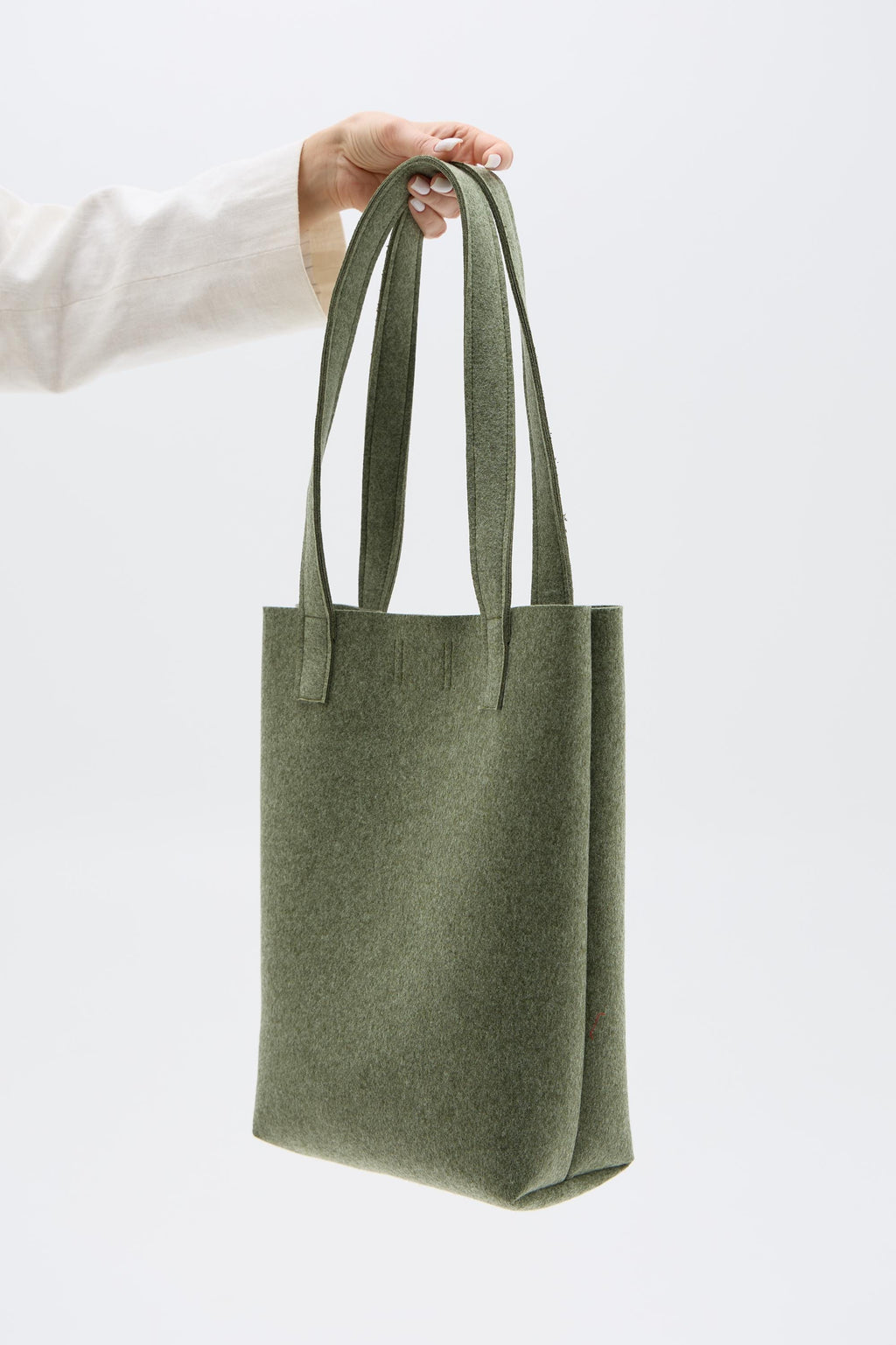 Green tote bag held by a person against a white background