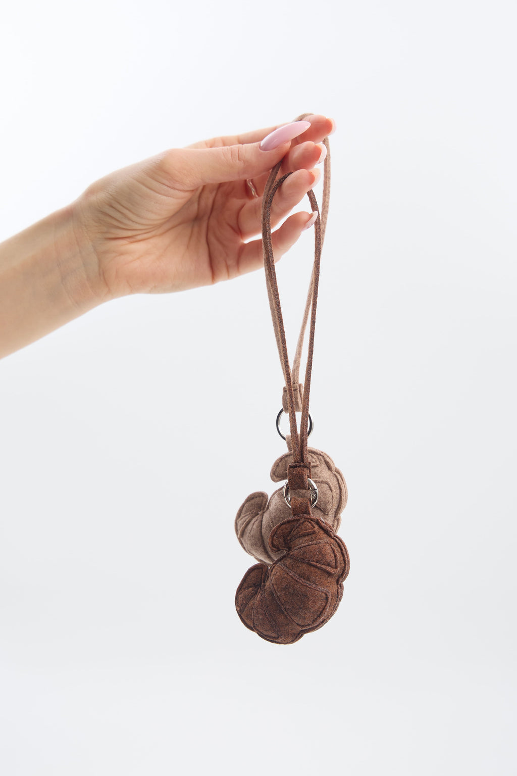 Hand holding a small brown eco felt keychain with a strap against a white background