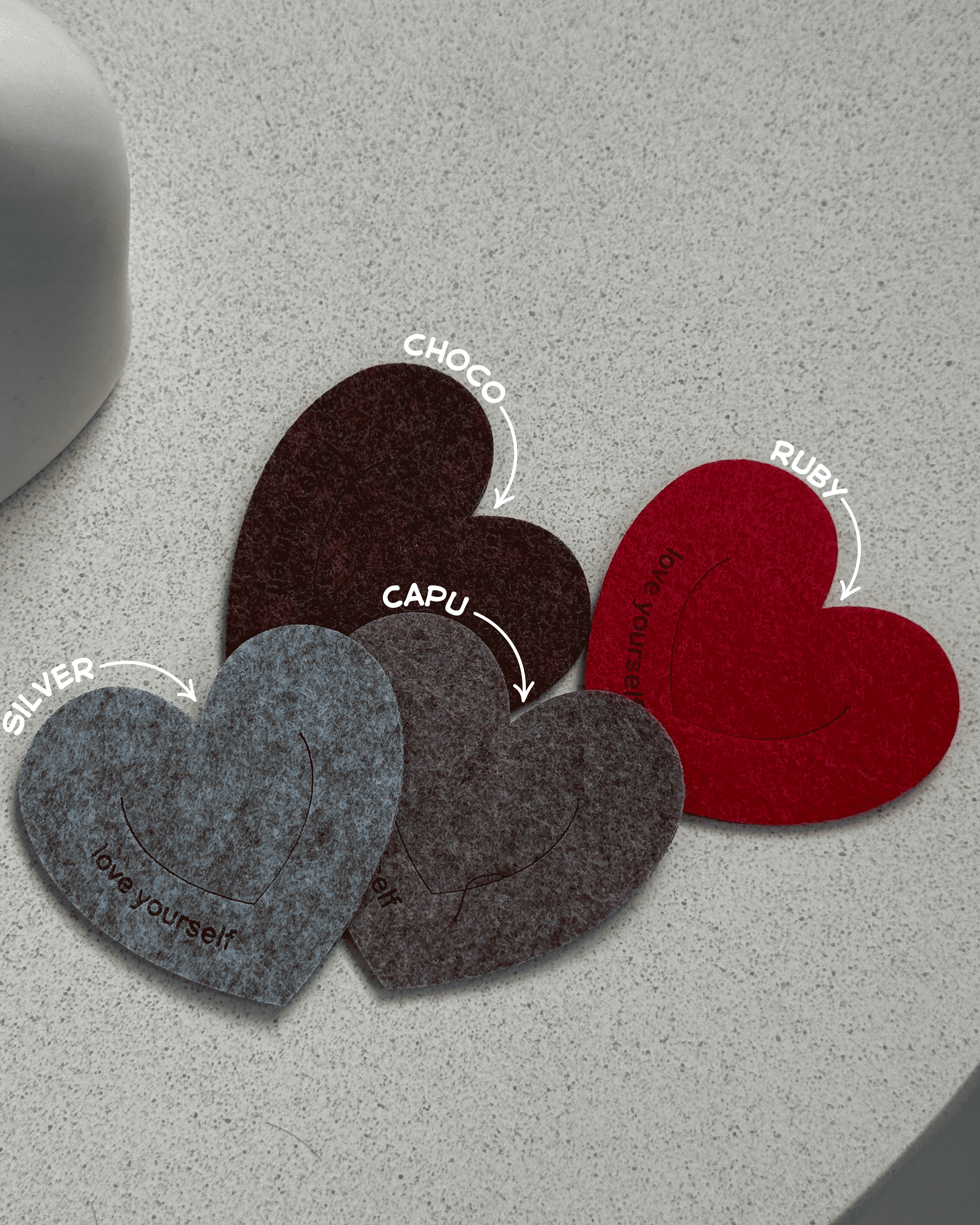 Heart-shaped bookmarks in silver, brown, and red on a gray surface
