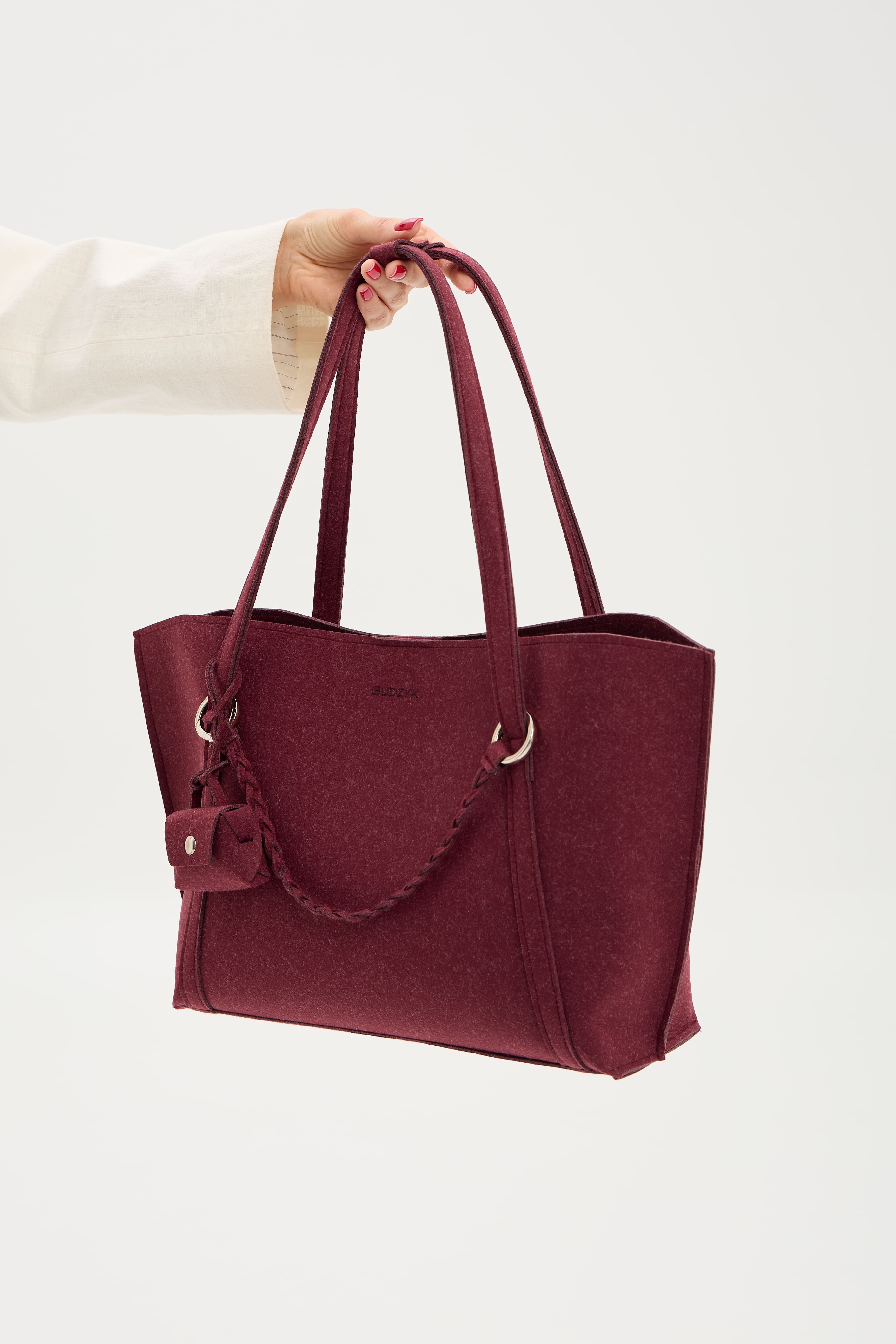 Maroon handbag held by a person on a white background