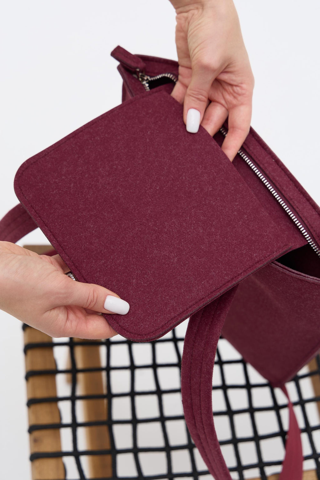 Maroon pouch held by hands against a white background
