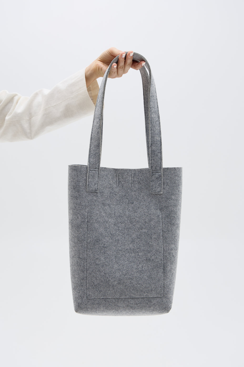 Gray tote bag held by a person against a white background