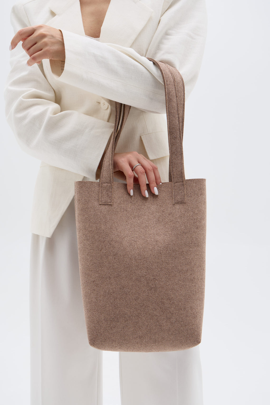 Person holding a beige tote bag against a white background